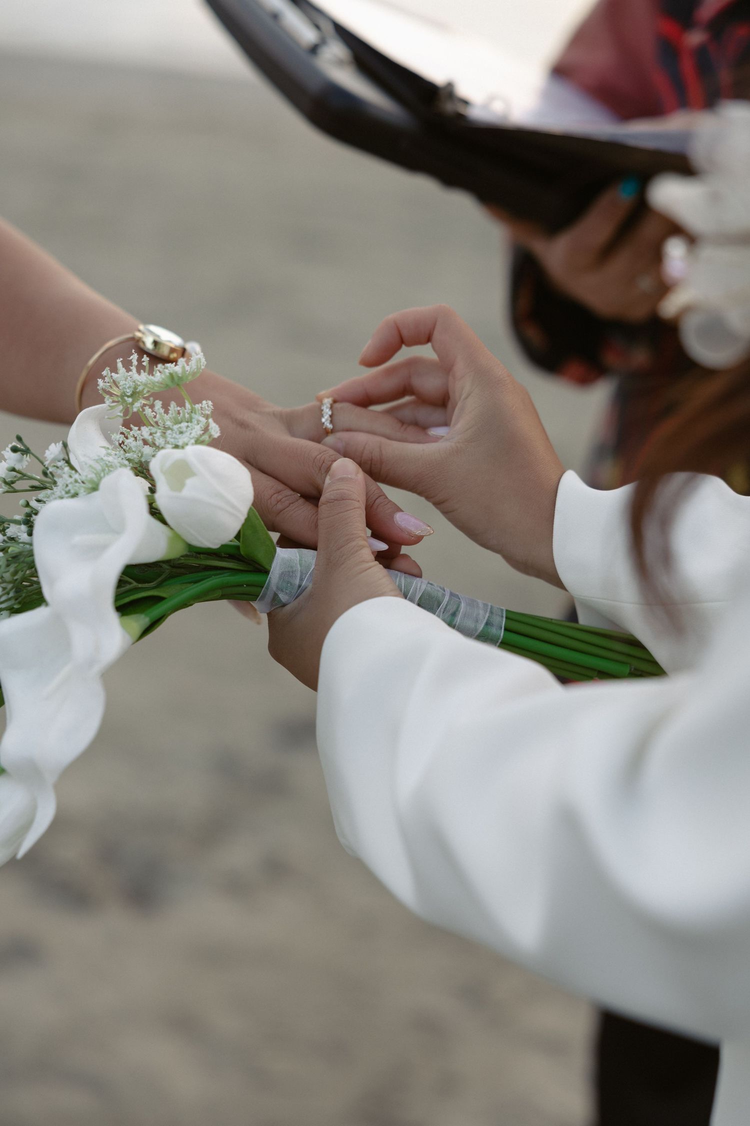 Hands holding white calla lily bouquets with baby's breath flowers.