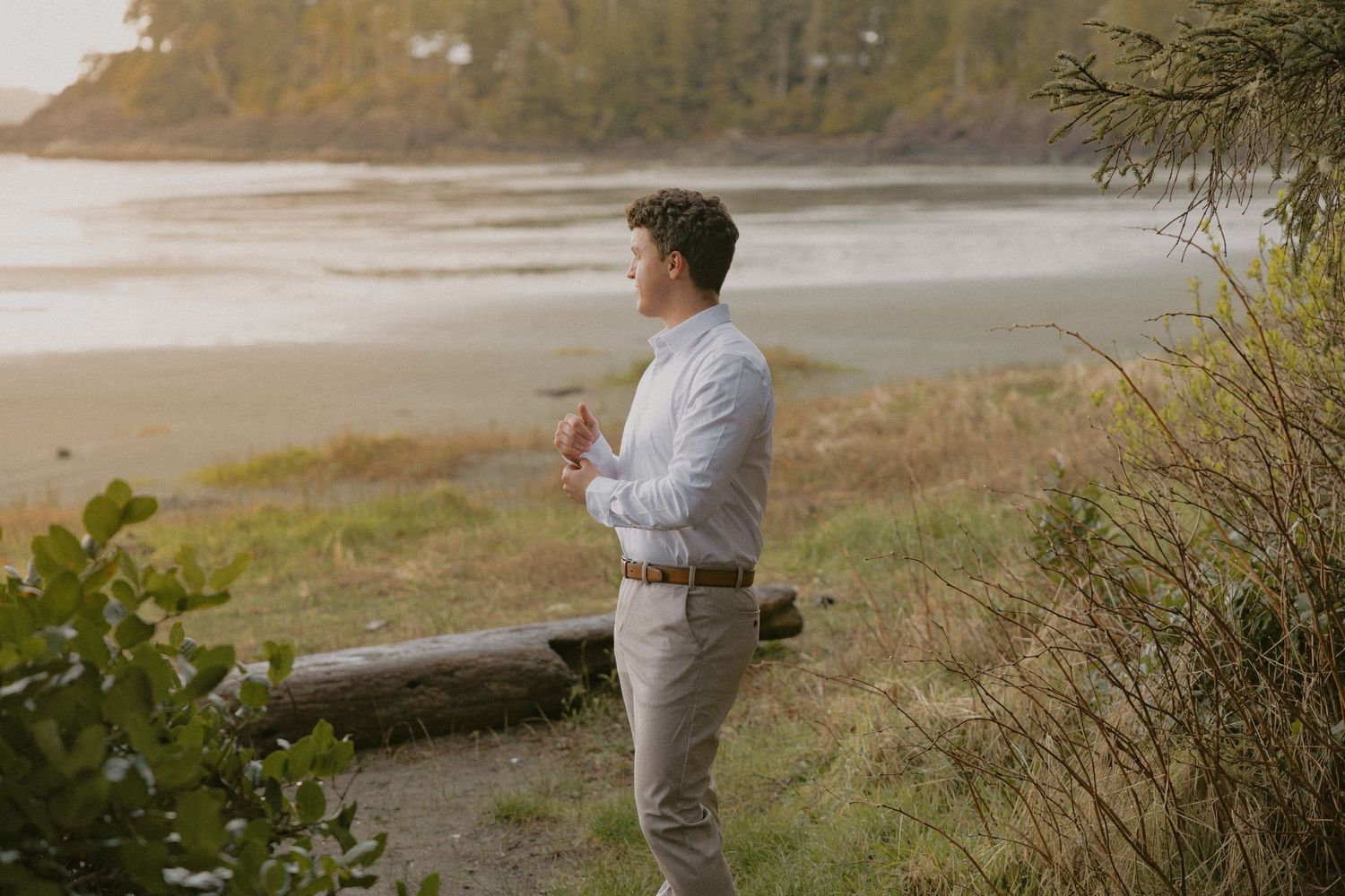 Groom looking out over the ocean at golden hour on Mackenzie Beach Tofino