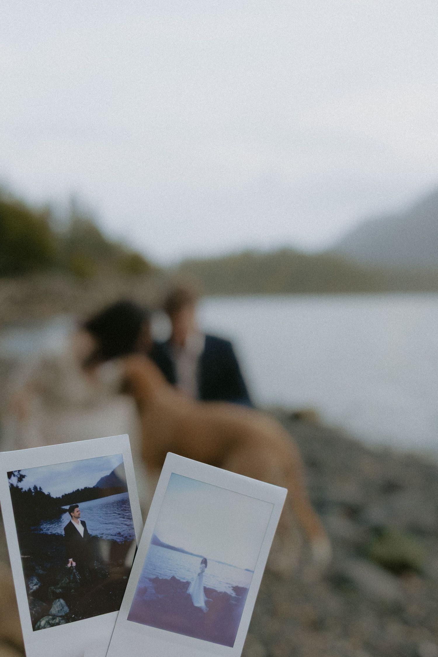 Polaroid photos scattered on rocks during a coastal wedding photoshoot.