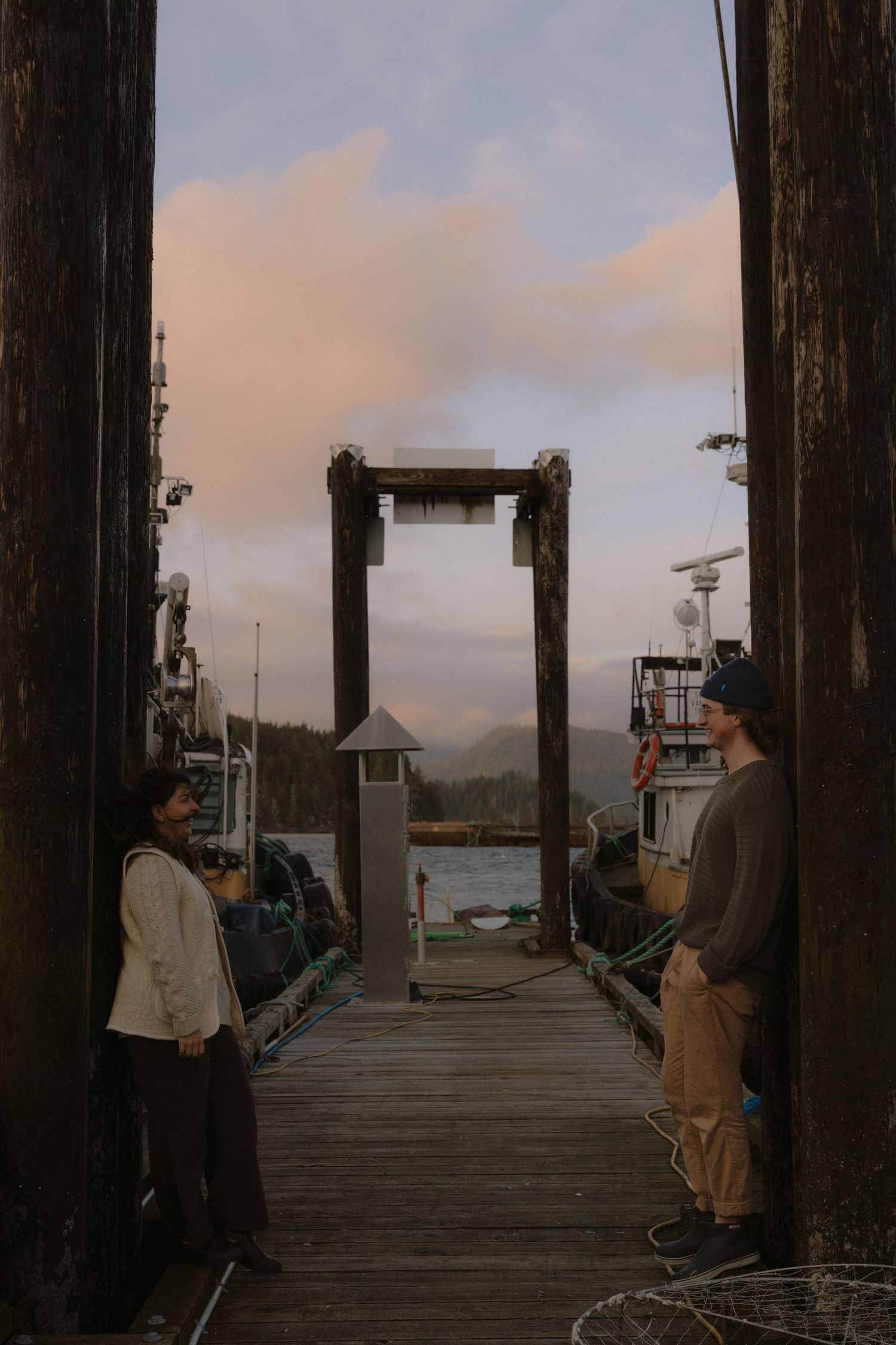 A scenic view of a harbor dock with people and boats silhouetted against a cloudy sunset.