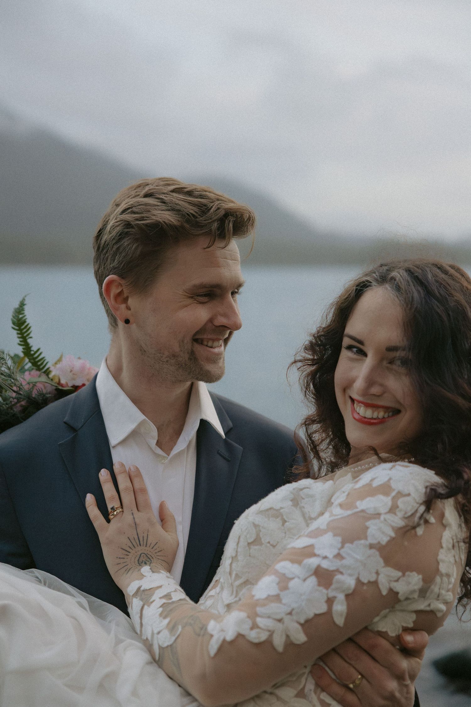 A couple shares laughter and tender moments during their wedding photoshoot by the water.