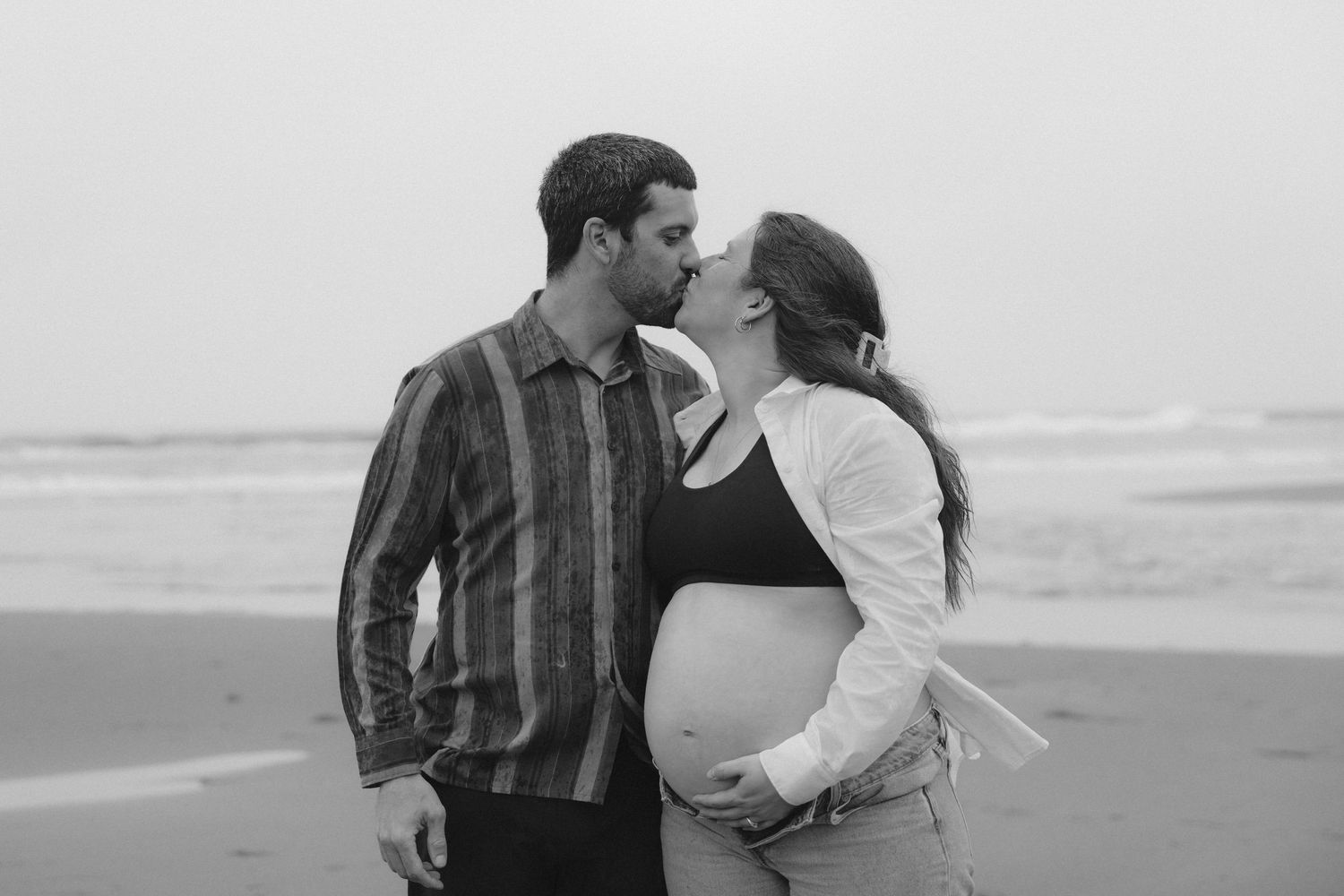 A romantic beach scene with a couple sharing an intimate moment by the ocean.