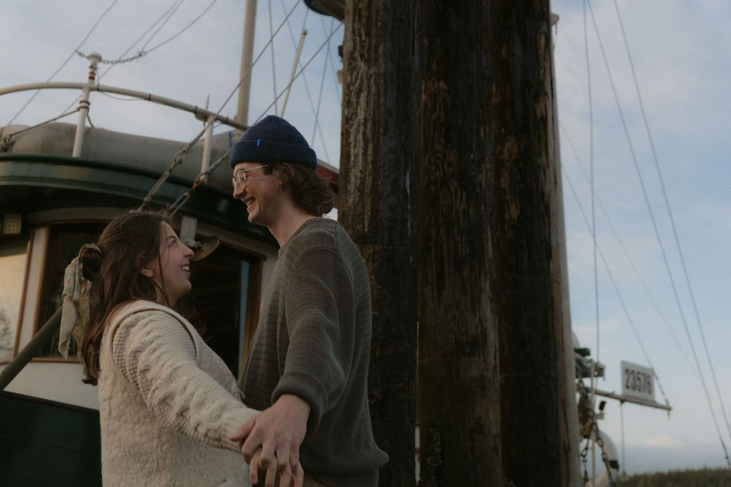 An intimate moment shared between two people at a marina with sailboat masts in the background.