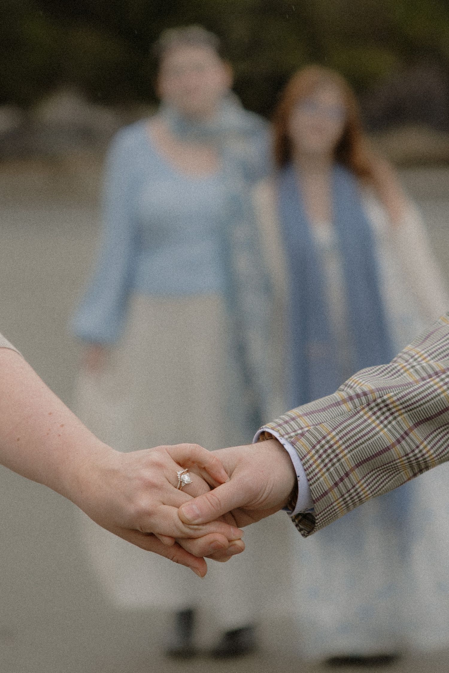 Close-up of hands holding while others stand in soft focus on a beach.