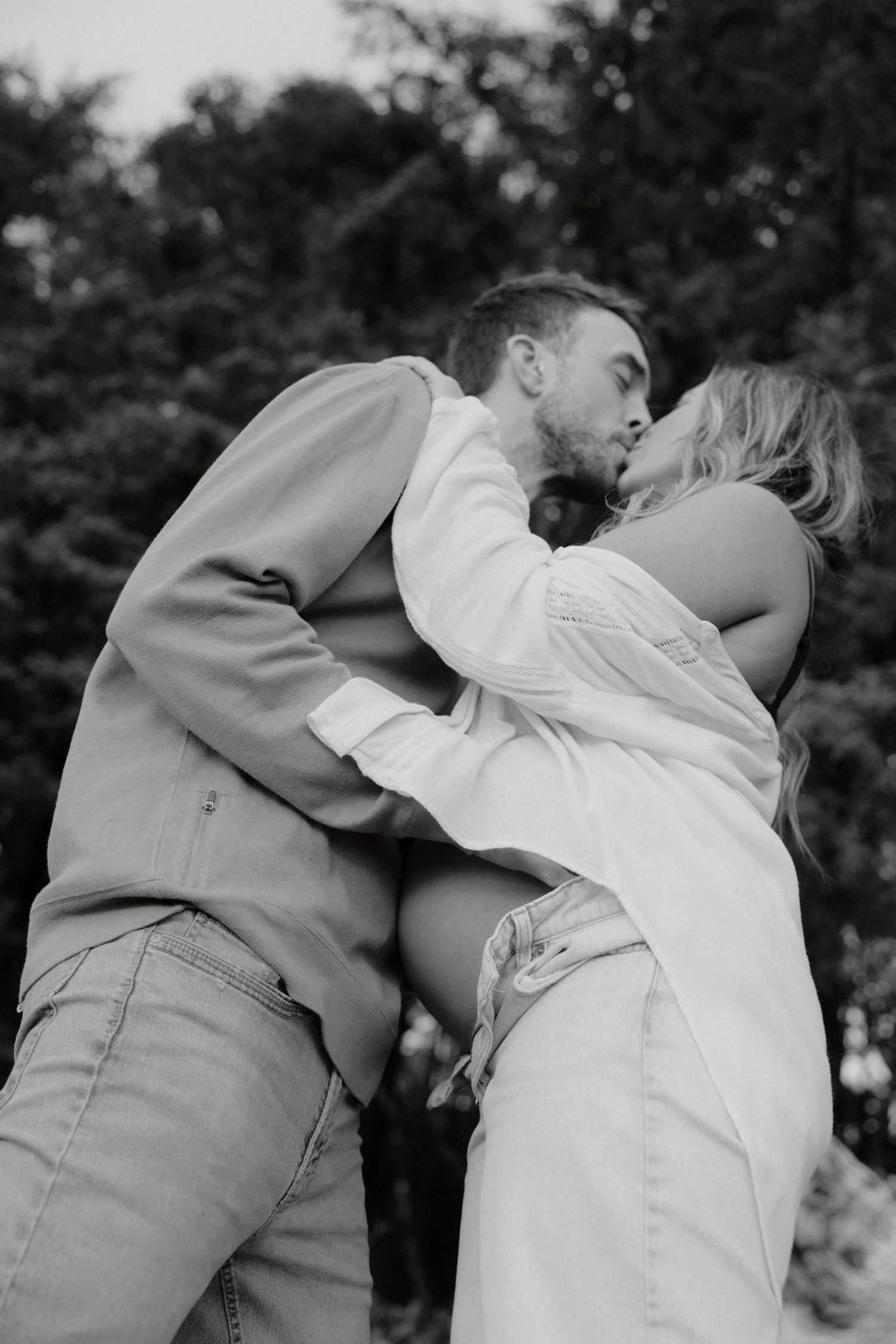 Black and white intimate maternity photos showing couple's tender embrace.