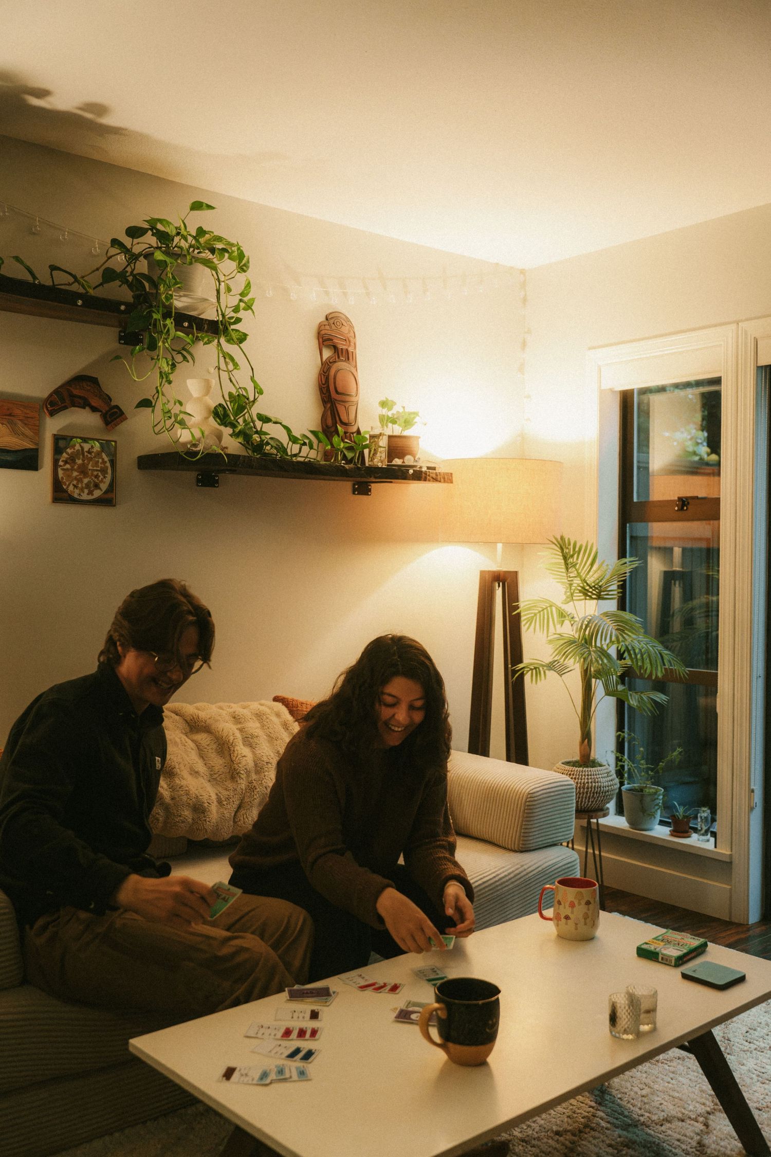 Two people playing a board game in a cozy living room with plants and modern decor