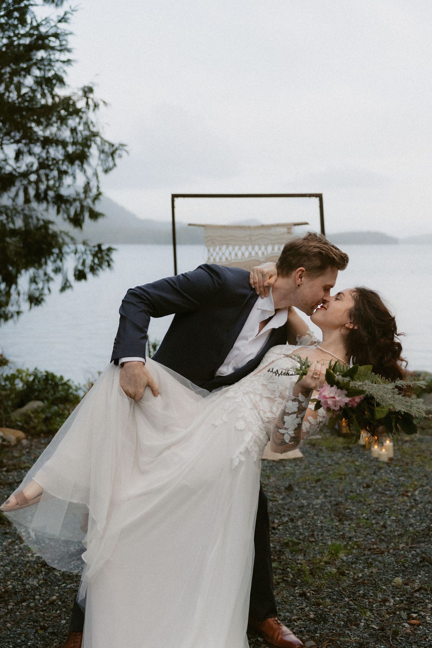 Tofino wedding ceremony dip kiss against a scenic mountain ocean backdrop in Clayoquot Sound