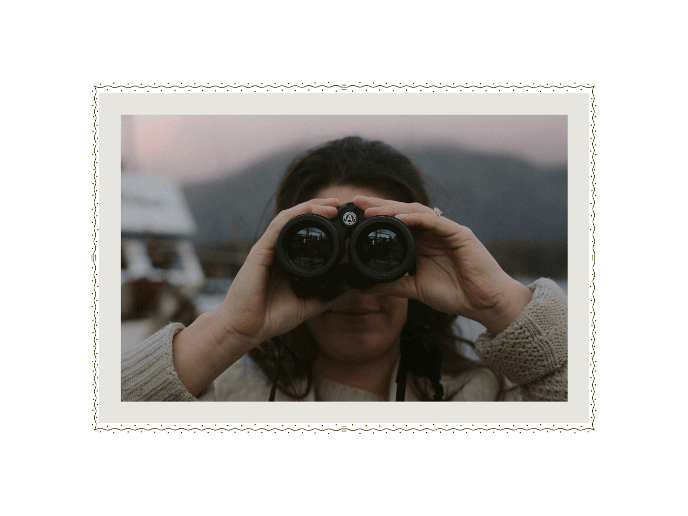 Mariana Tofino Wedding Photographer looking through binoculars against moody sky in Tofino