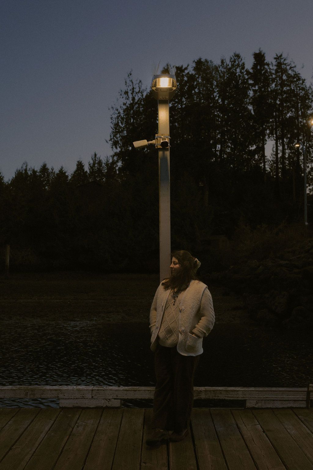 Ucluelet wedding photographer Illuminated lamp post stands on a wooden dock during blue hour