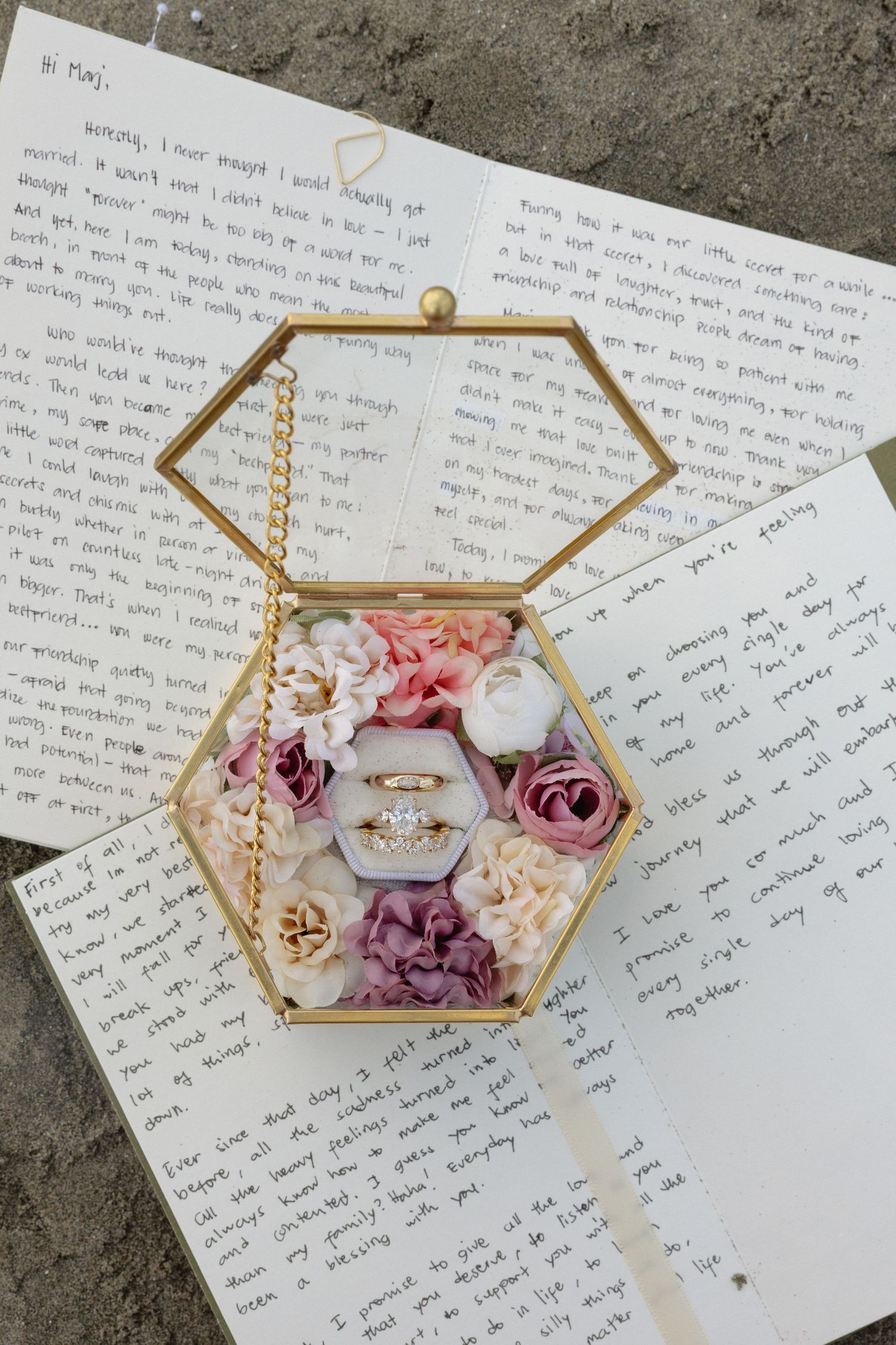 Handwritten wedding vows with gold geometric box filled with pink and purple roses.