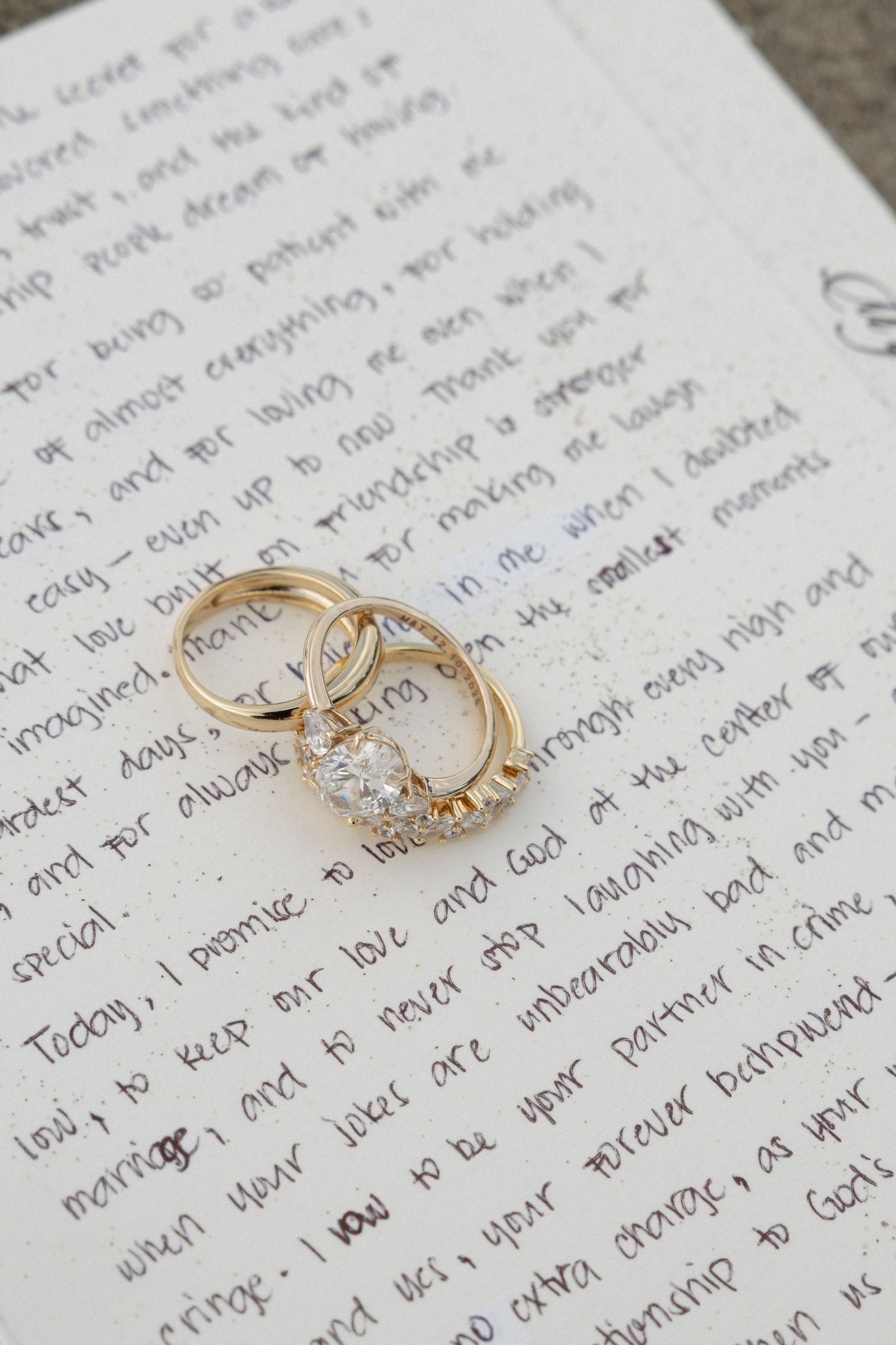 Wedding rings resting on handwritten pages of personal vows.