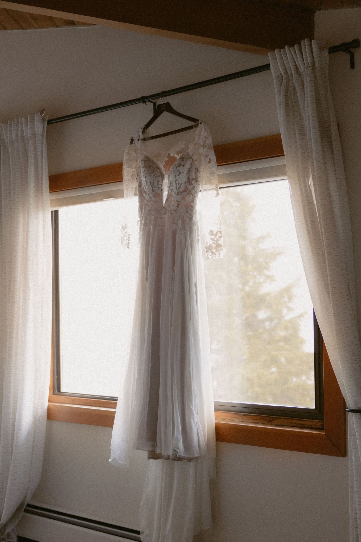 Tofino wedding bridal dress hanging on the window overlooking Clayoquot Sound