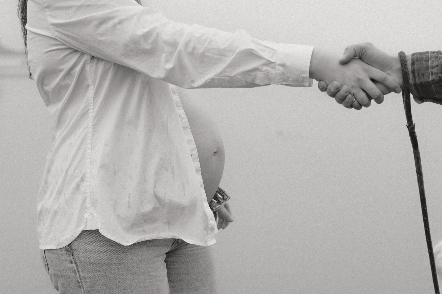 A black and white close-up image of two people shaking hands against a plain background.
