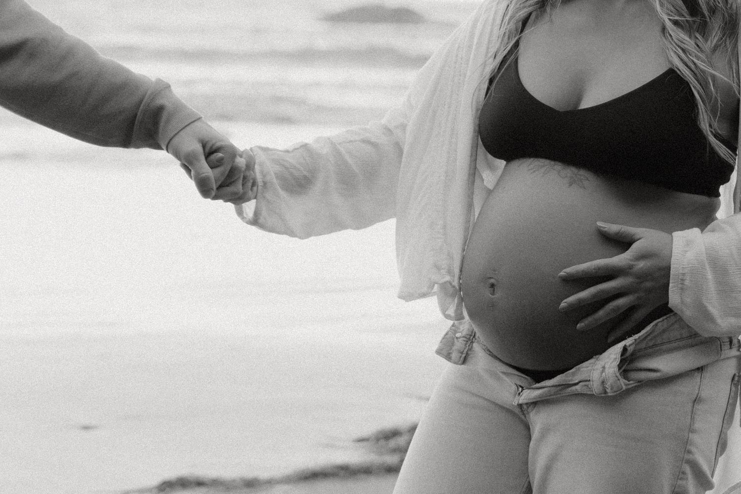 Tofino pregnant couple near South Chesterman Beach holding hands and baby bump by the ocean