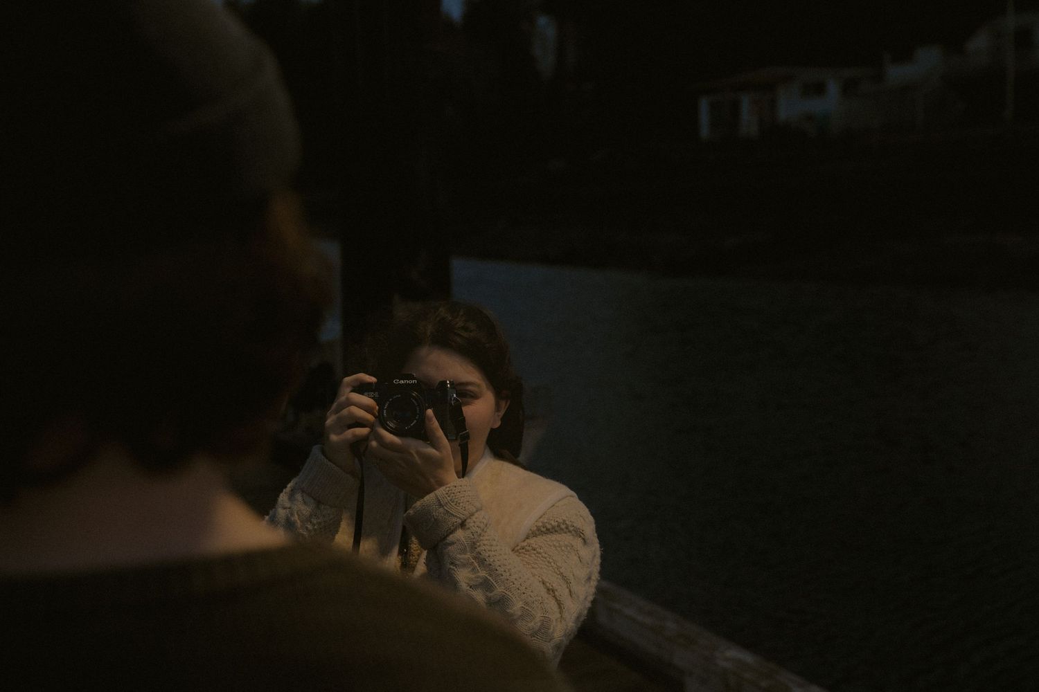 Shadowy figures photographing on a dock during evening hours.