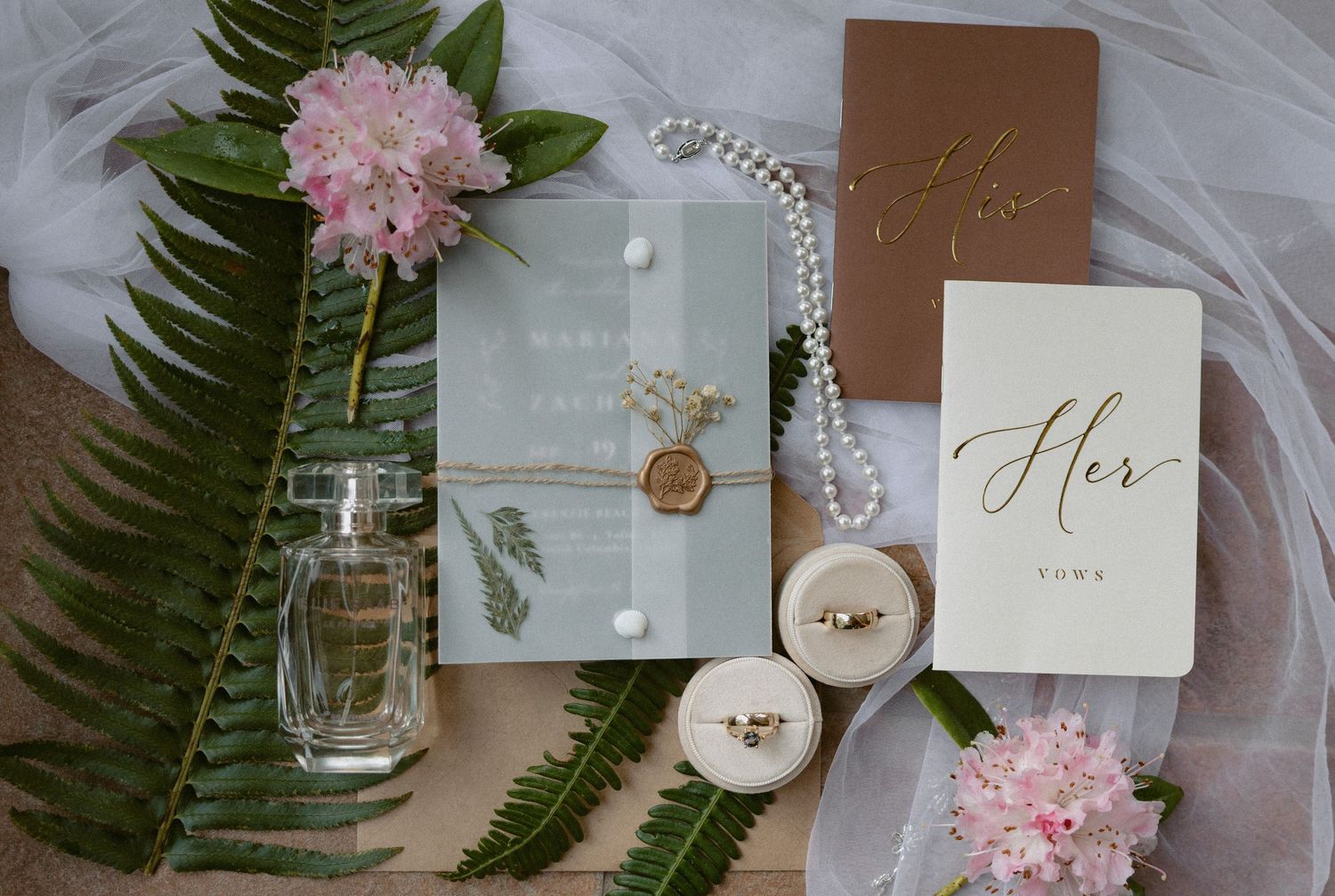 Tofino wedding stationery and decor flat lay with pink flowers and ferns on veil