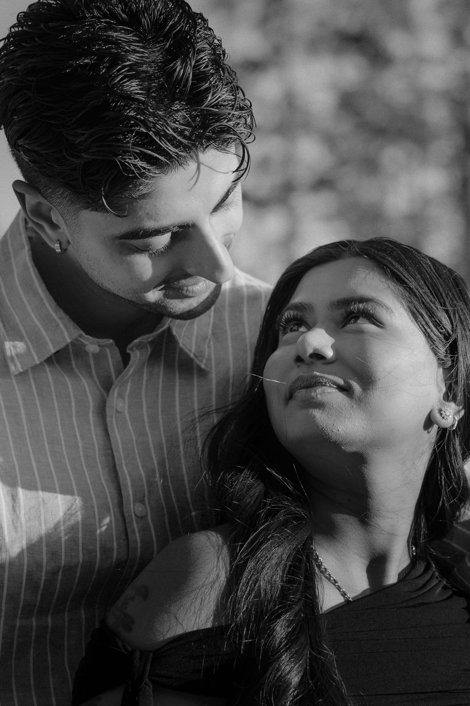 Black and white close-up of a couple gazing at each other tenderly in natural light.