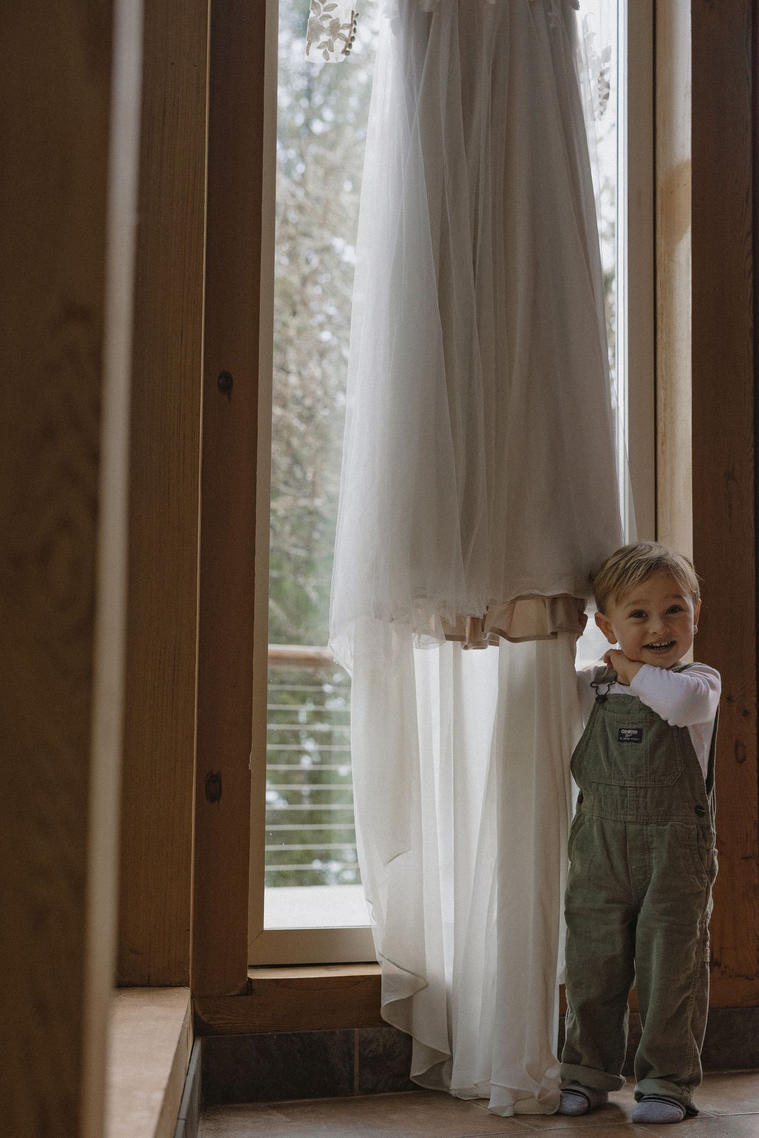 White curtains flow gently in front of large windows in a rustic wooden room.