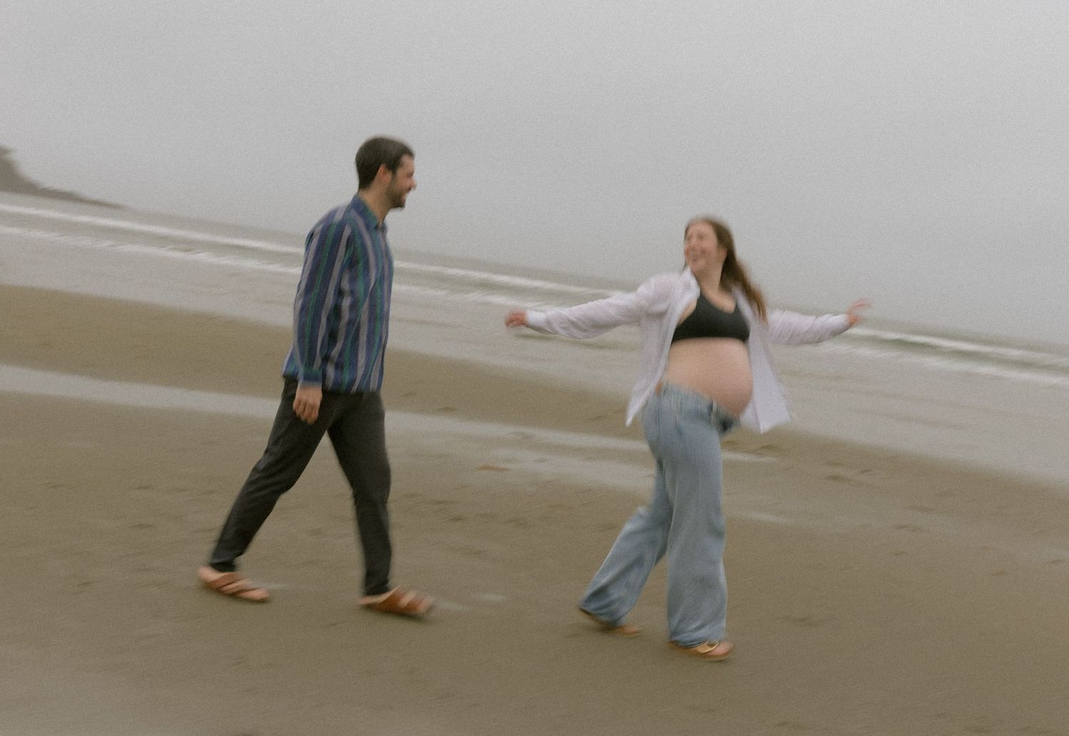 Couple enjoying a playful moment during beach maternity session.
