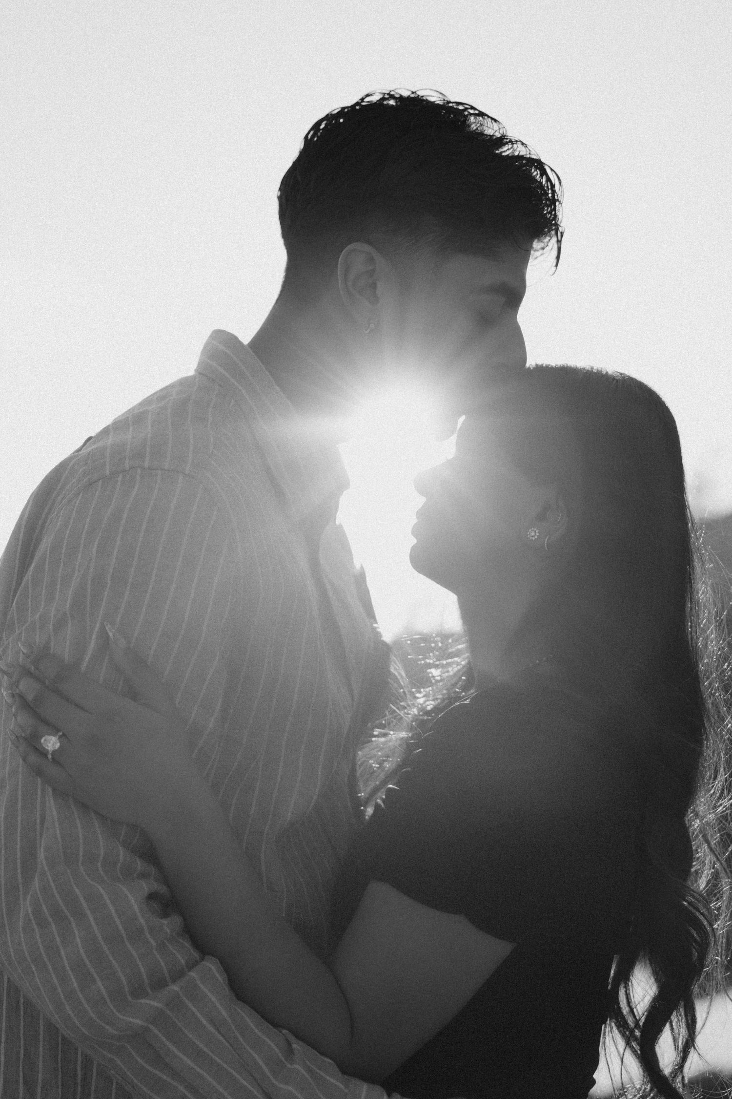 Romantic couple silhouette with sun flare between them in black and white.