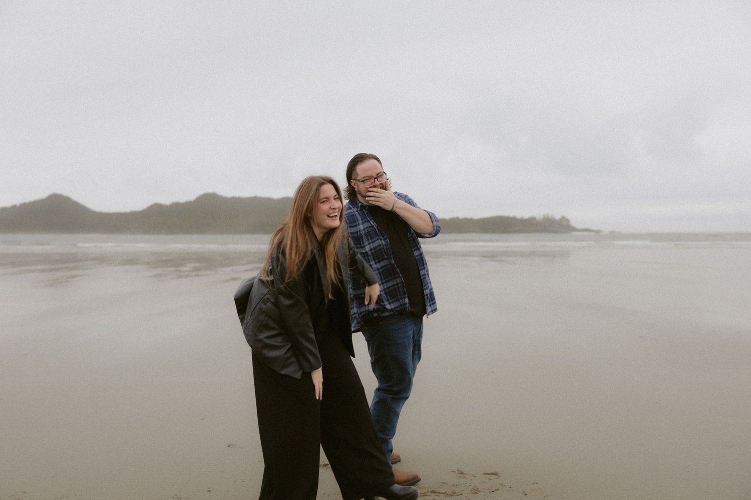 Tofino couple post-proposal on Chesterman Beach holding hands and laughing