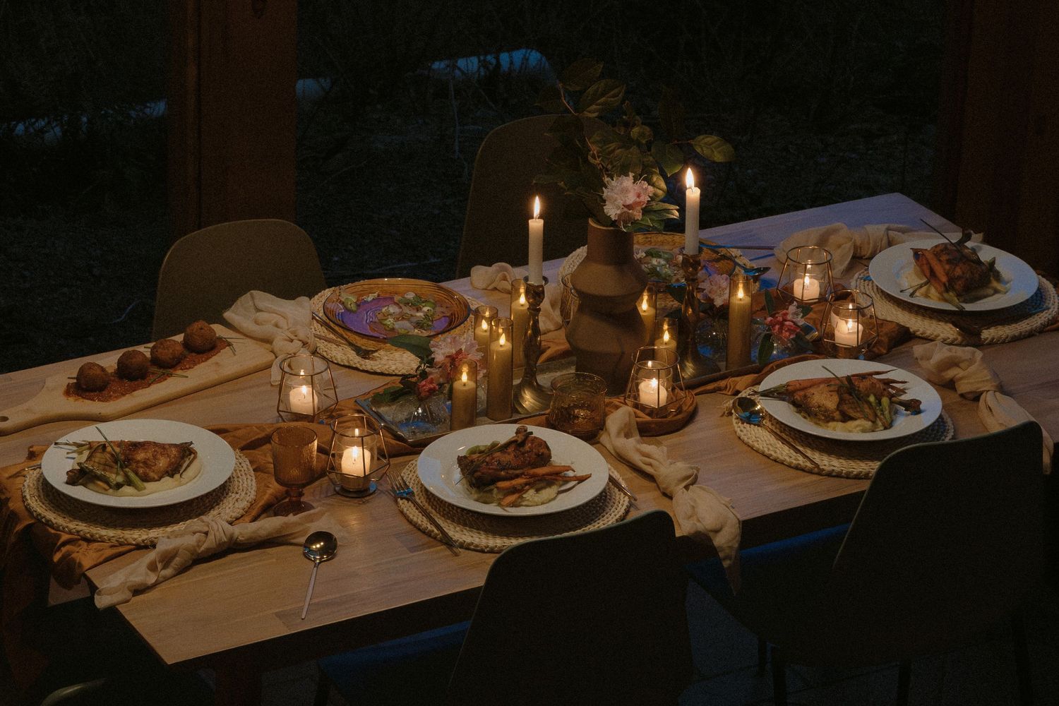 A romantic dinner table set with candles, plates, and warm ambient lighting.