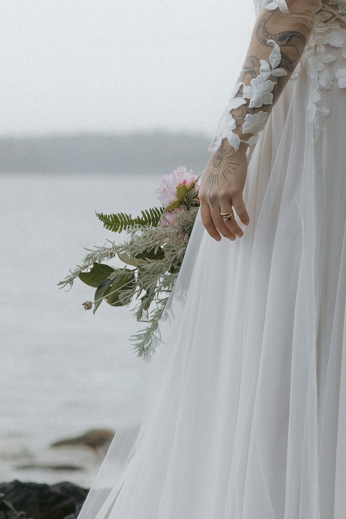 Detail shot of a flowing white wedding dress with delicate lace and floral decorations.