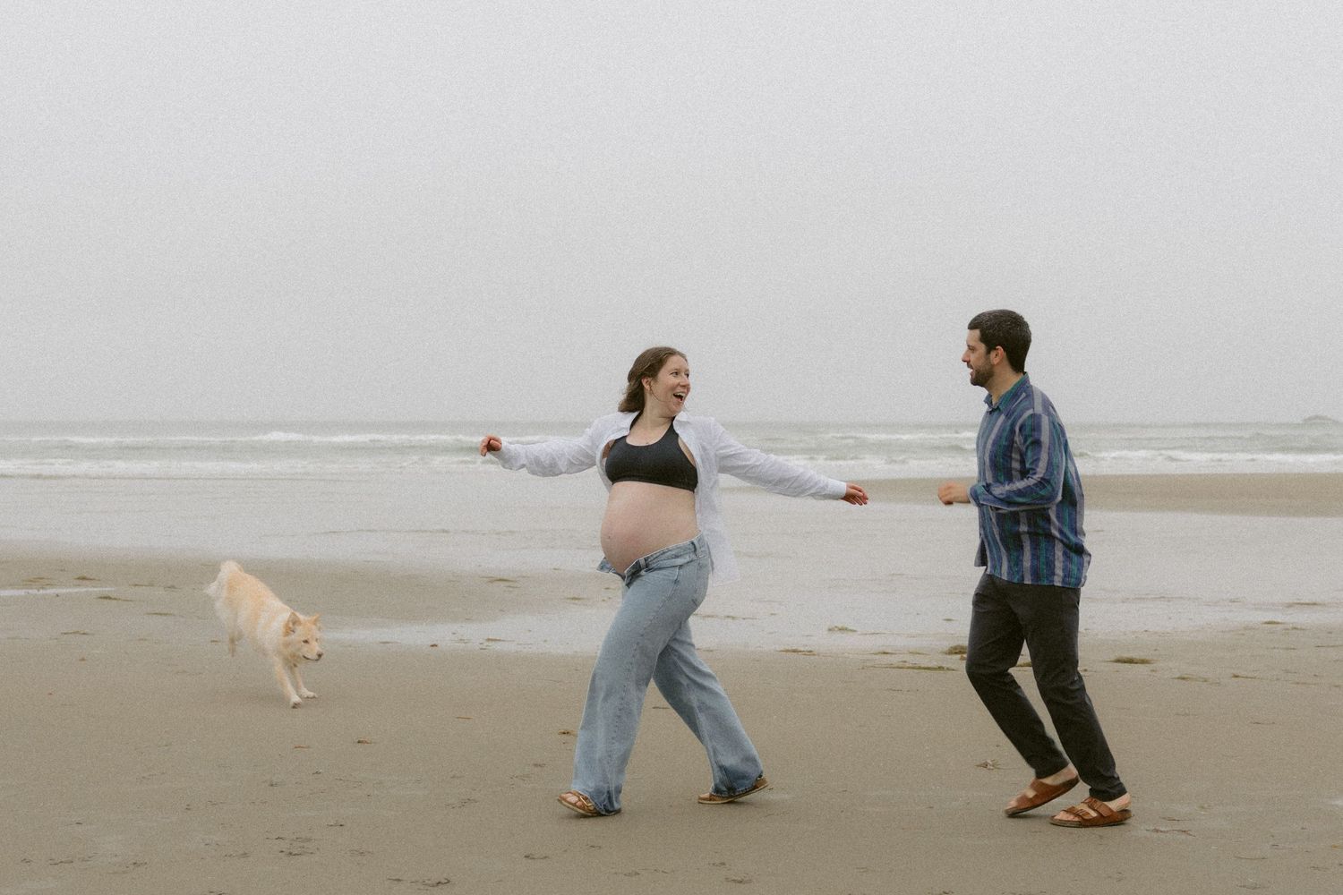 Wide angle shot of couple dancing together on an overcast beach.