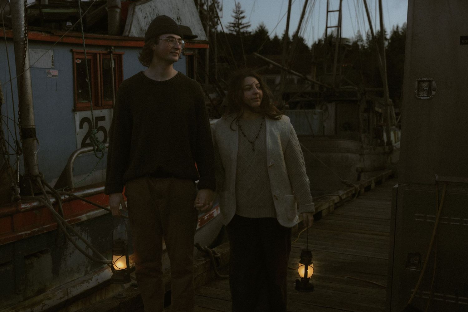 A romantic evening scene on a dock with warm lantern lighting and boats in the background.