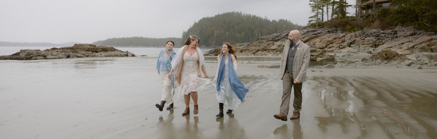 Family walking together along a scenic rocky beach shoreline during sunset on a cloudy evening.