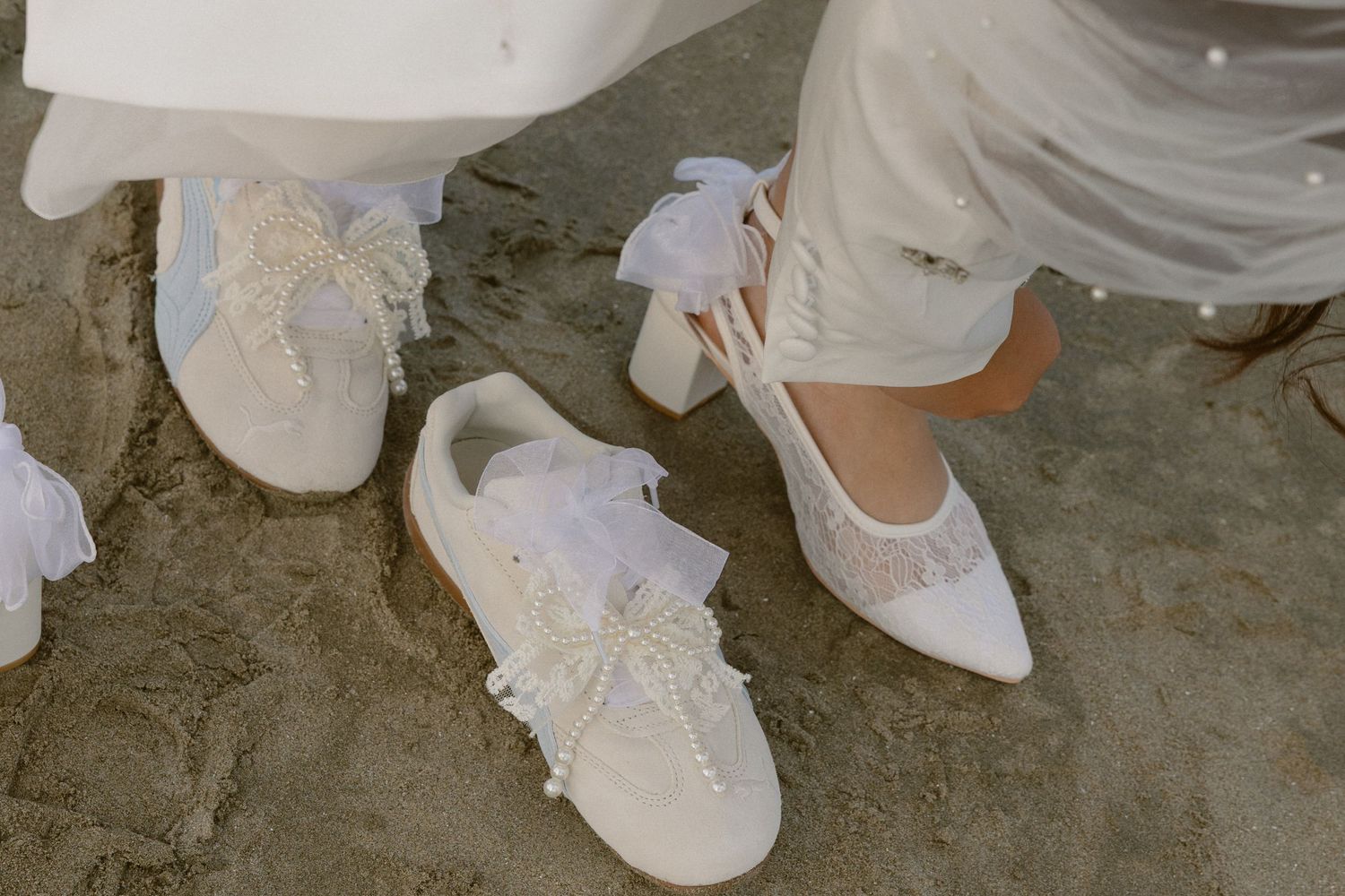 White sneakers and dress hems visible against sandy ground.