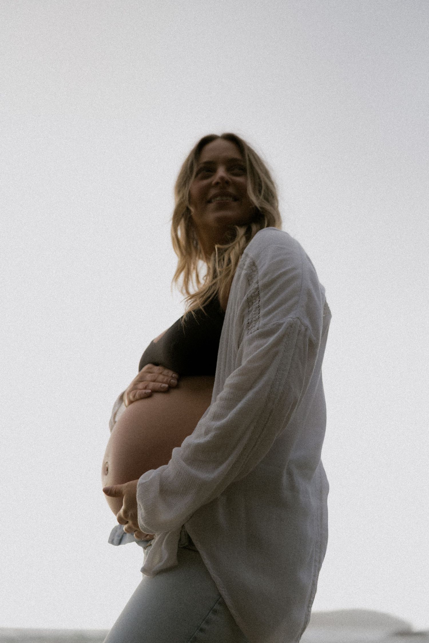 Artistic maternity portraits showing silhouette against bright sky.