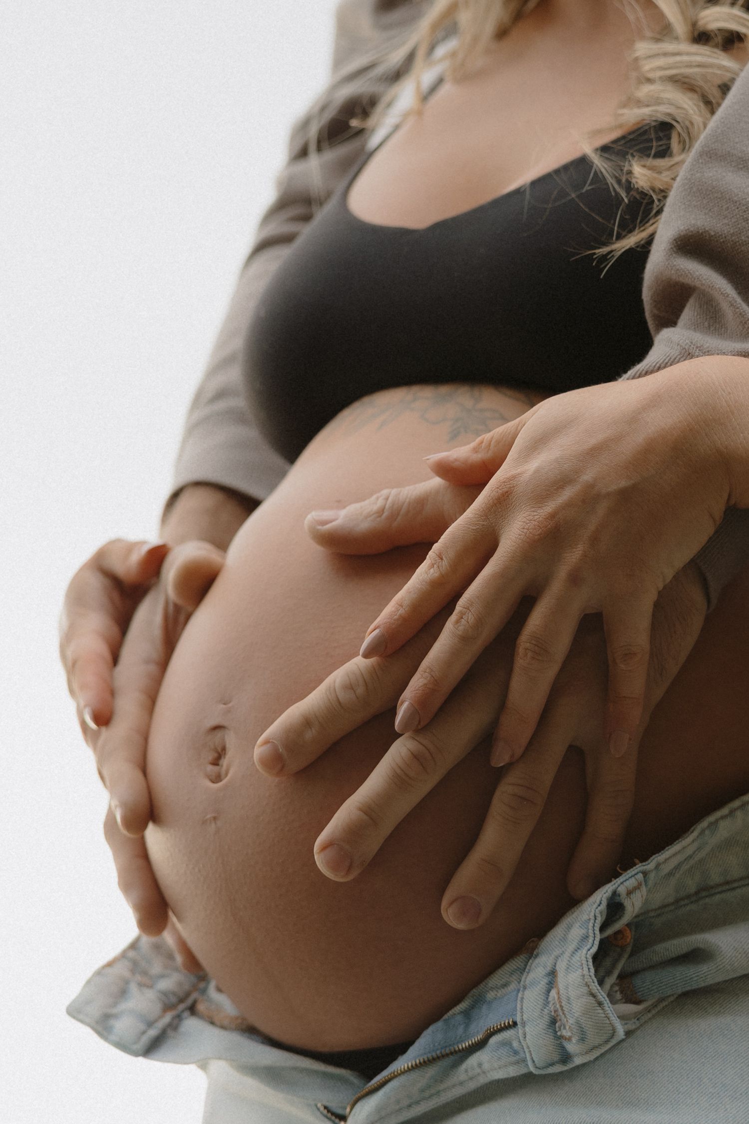 Close-up of hands gently cradling a pregnant belly in a maternity photo.