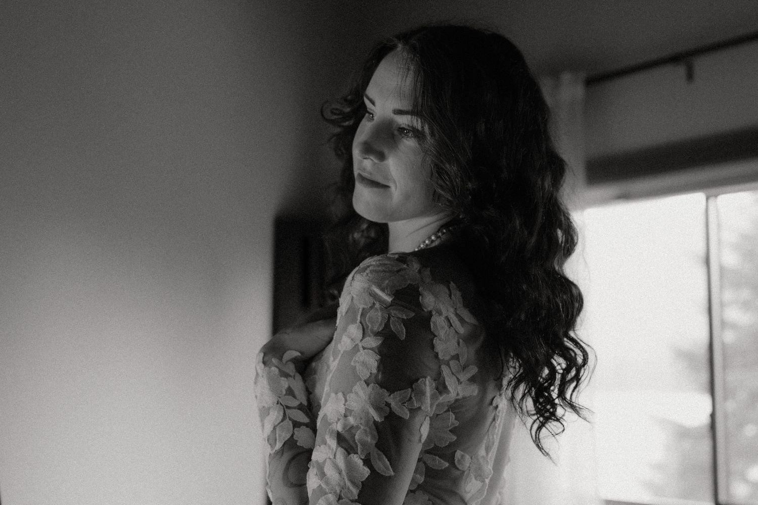 Dreamy black and white portrait with soft window light creating a romantic atmosphere.