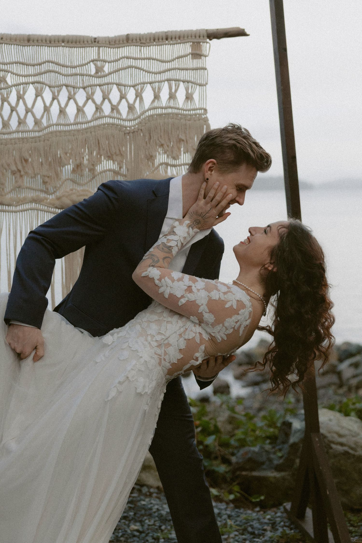 Tofino elopement couple shares an intimate dip pose against a backdrop with decorative macrame hangings