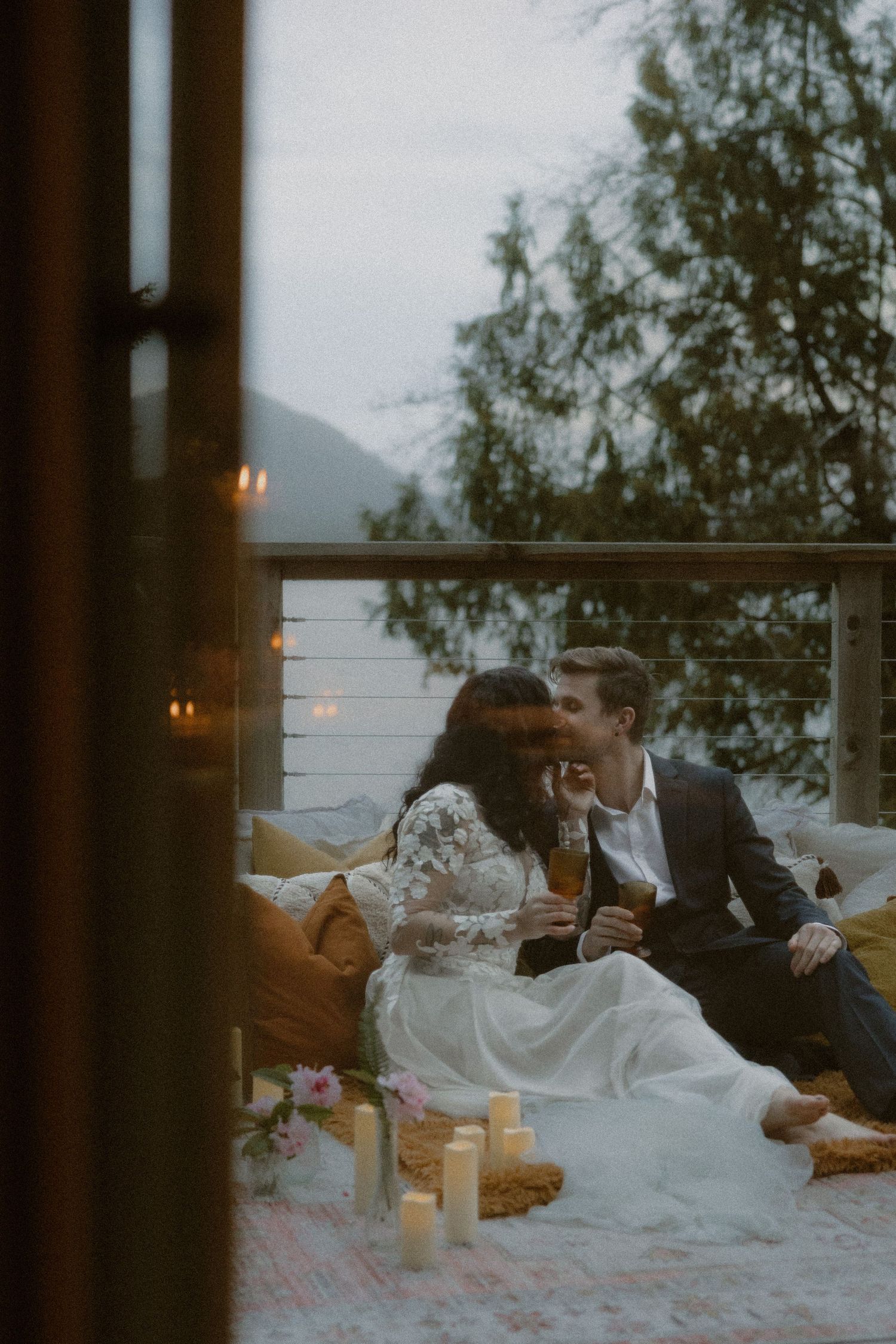 An intimate candlelit moment on a balcony with mountain and lake views at twilight.