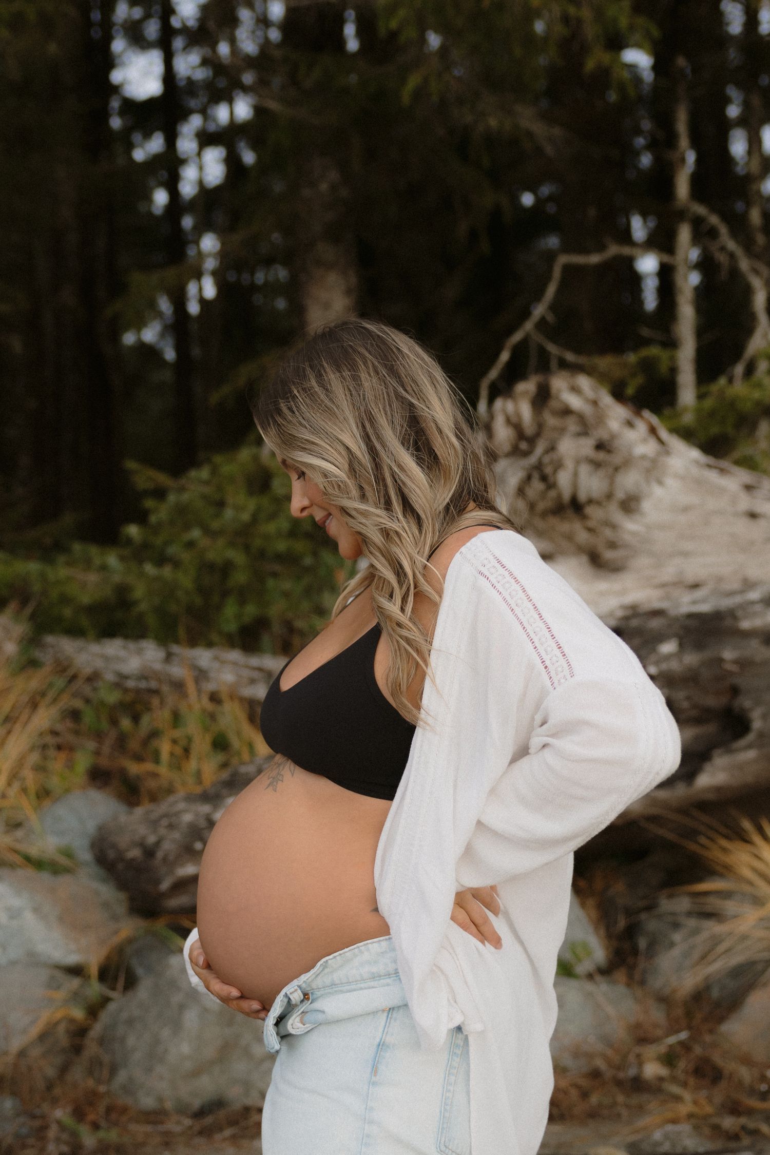 Natural outdoor maternity photos among rocks and trees showing growing baby bump.