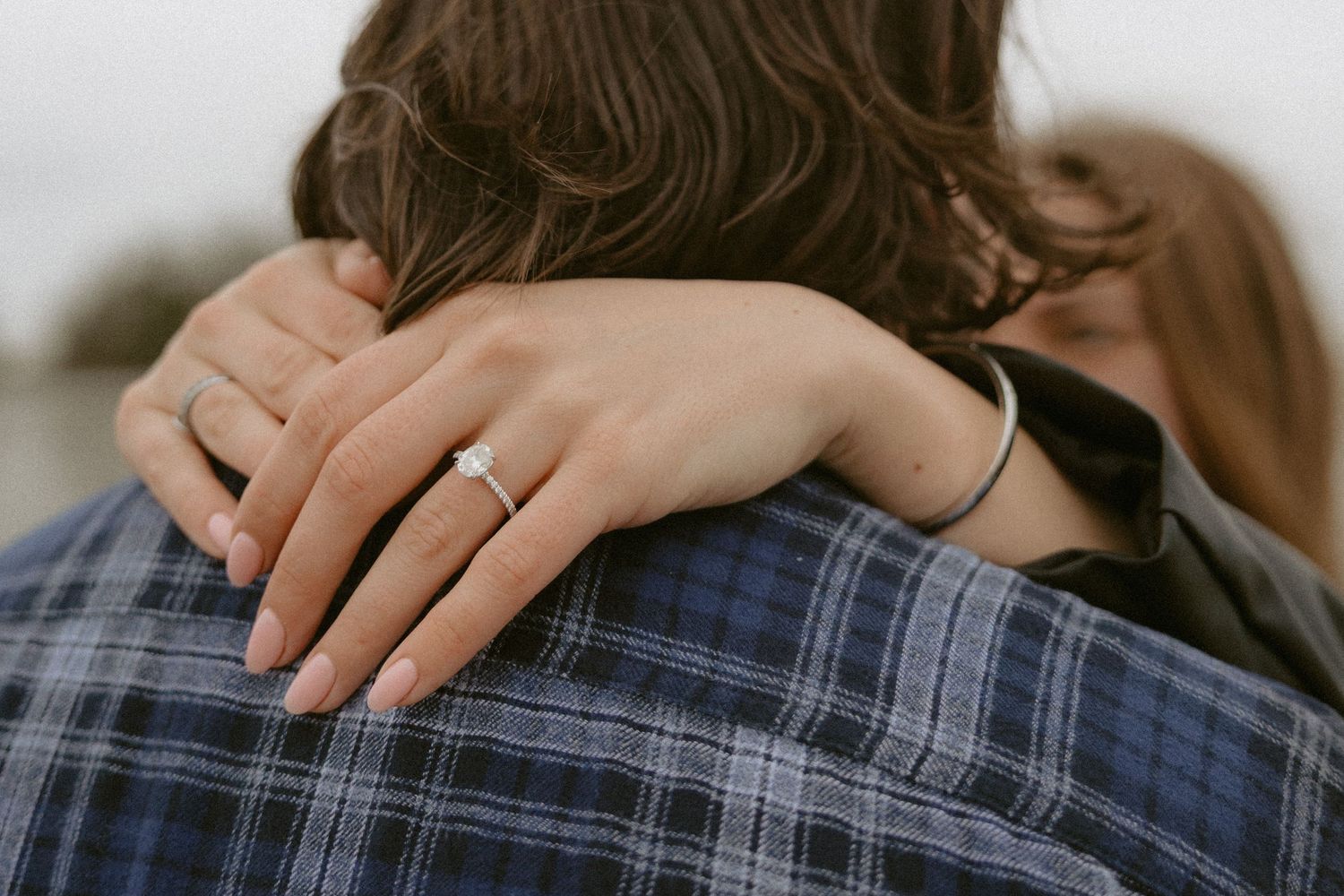 Tofino engagement intimate embrace showing hands with engagement ring against cloudy beach backdrop