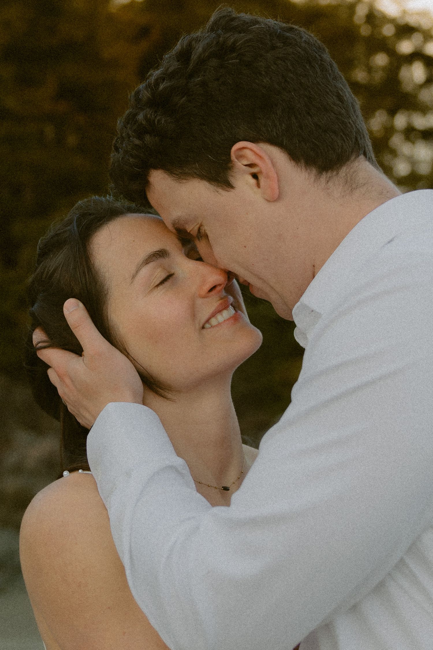 An intimate moment captured between a Tofino couple in wedding attire against a dark background