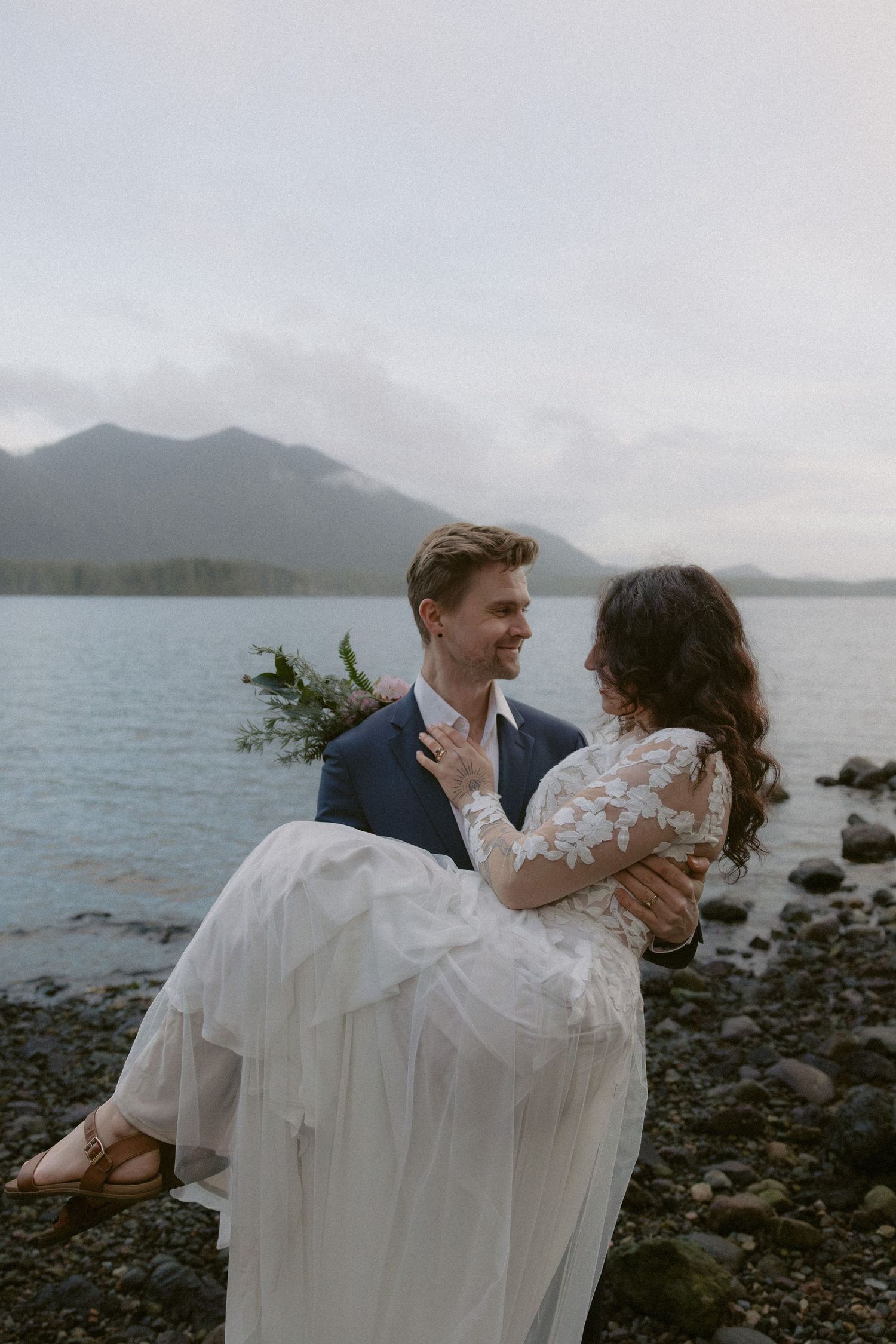 A romantic dance captured on a rocky beach with mountains and water in the background.