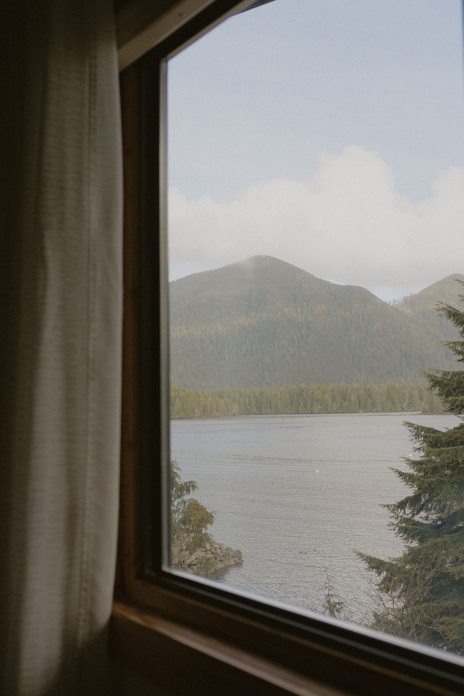 Tofino wedding venue view of mountain lake through window framed by white curtains