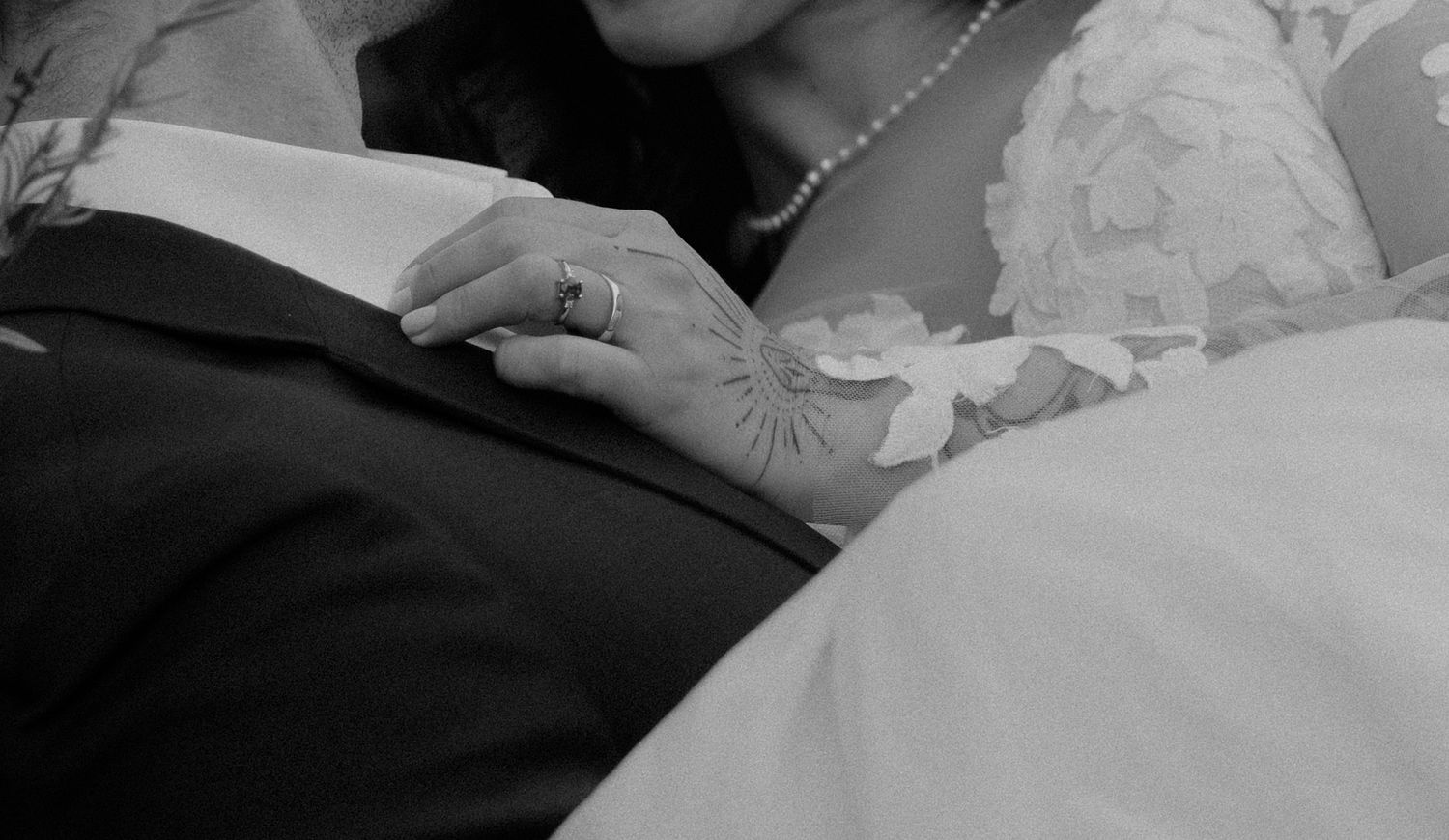 Elegant lace details and delicate beading adorn a white wedding gown hanging in soft window light.