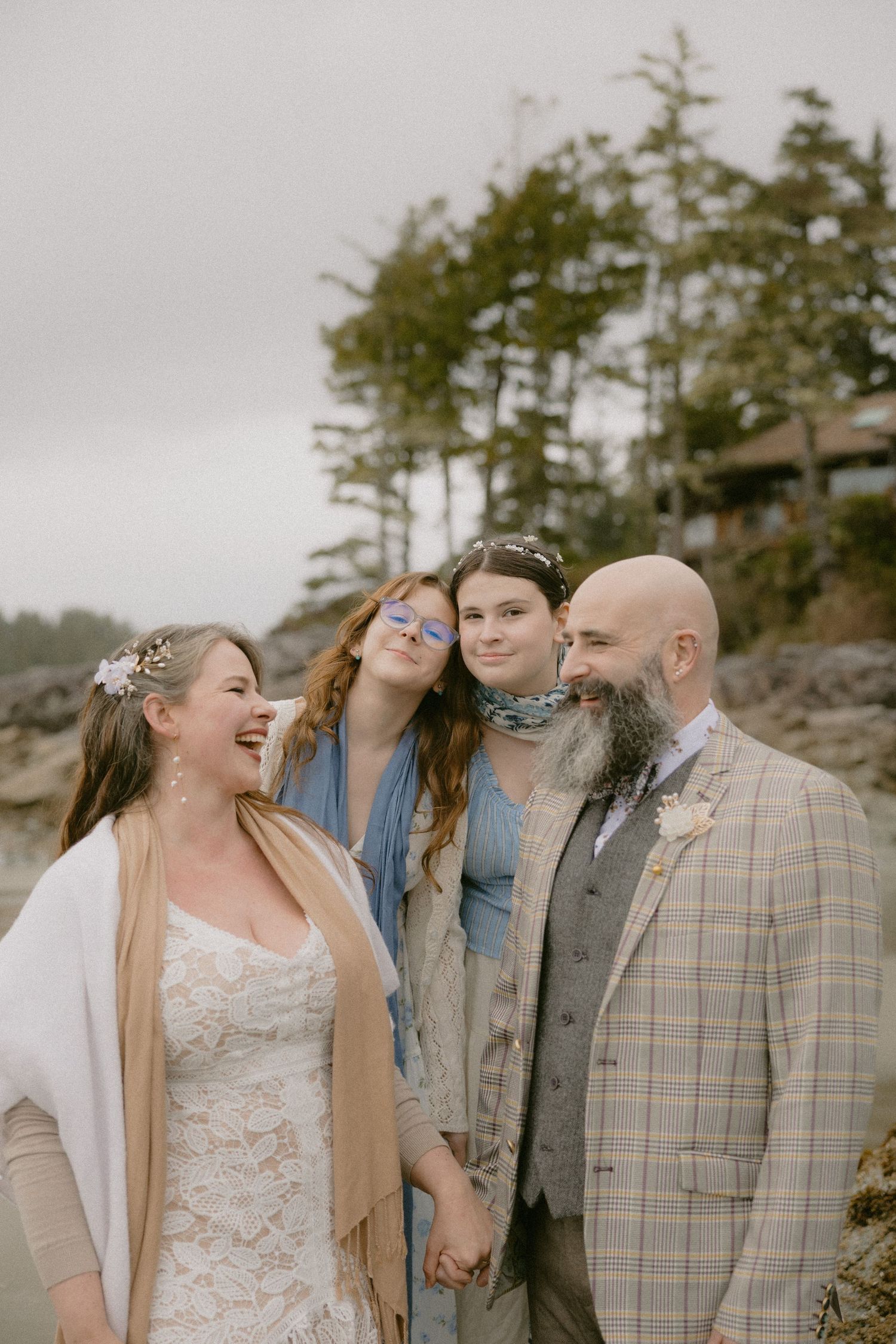 Wedding group enjoying a lighthearted moment against a natural backdrop of trees and rocks.