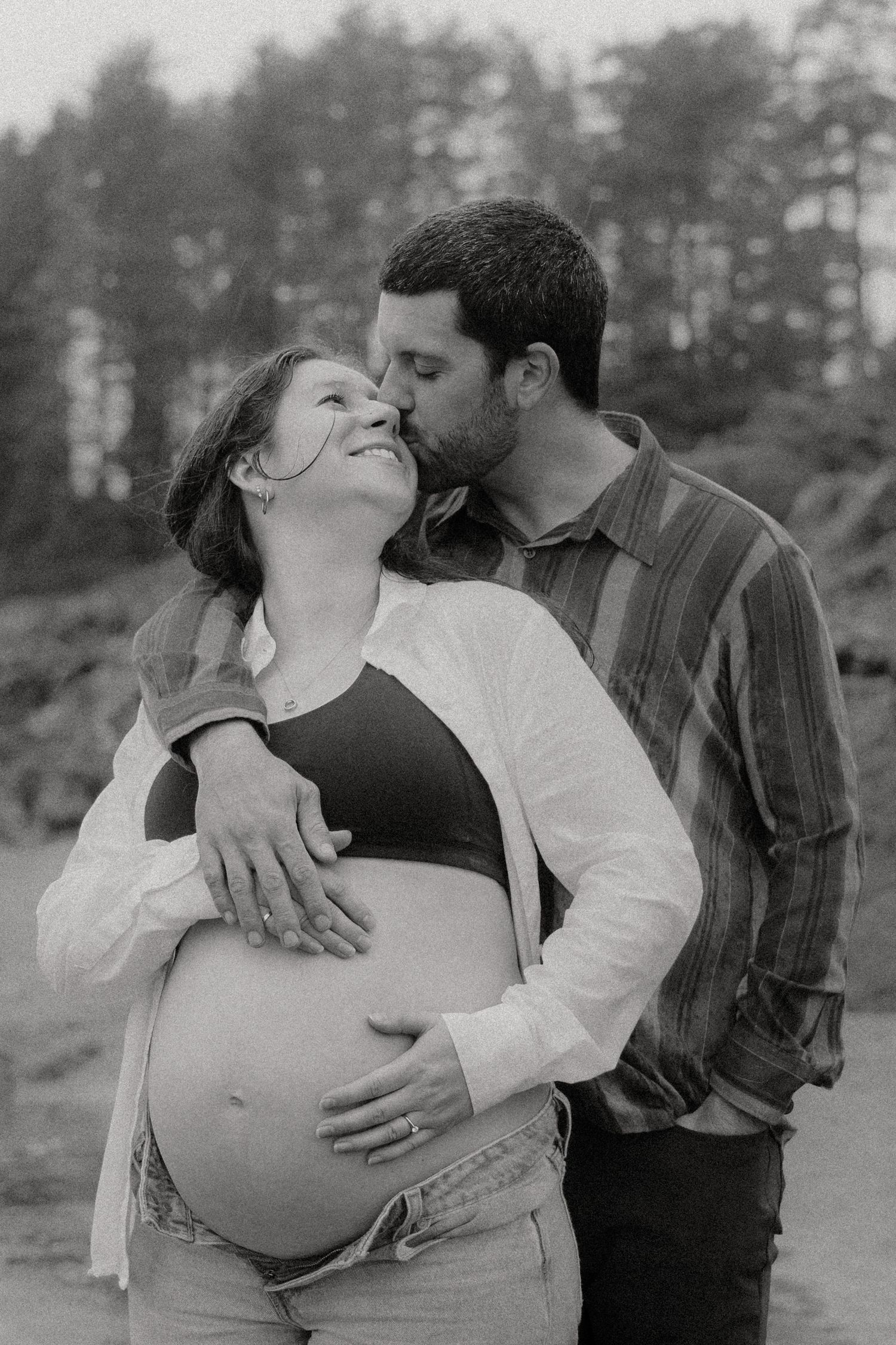 An intimate maternity photoshoot sequence in black and white among trees.