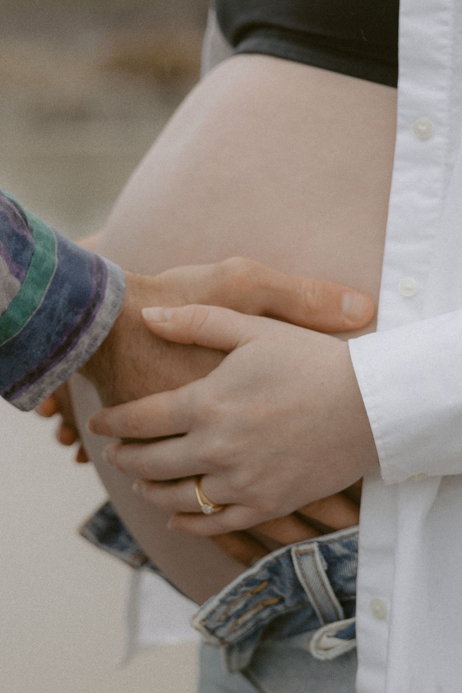 Close-up of hands touching with one person wearing a gold wedding ring.