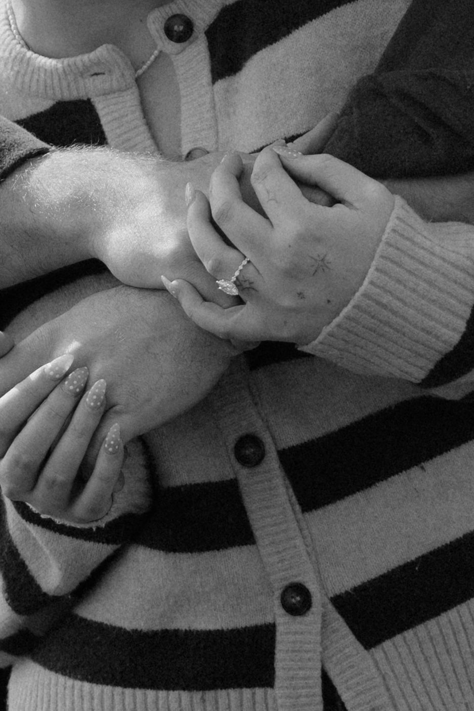 Close-up black and white photo of engagement ring on womans hand with star tattoos.