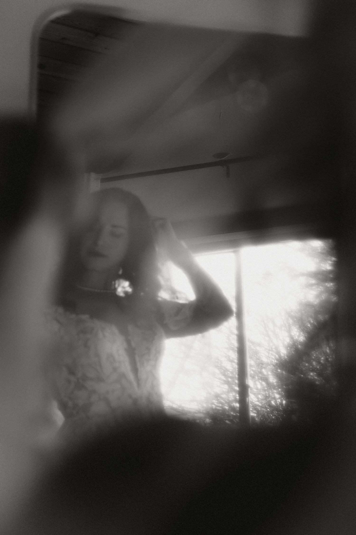 Dreamy wedding black and white photograph of the bride through her veil with soft focus and window light