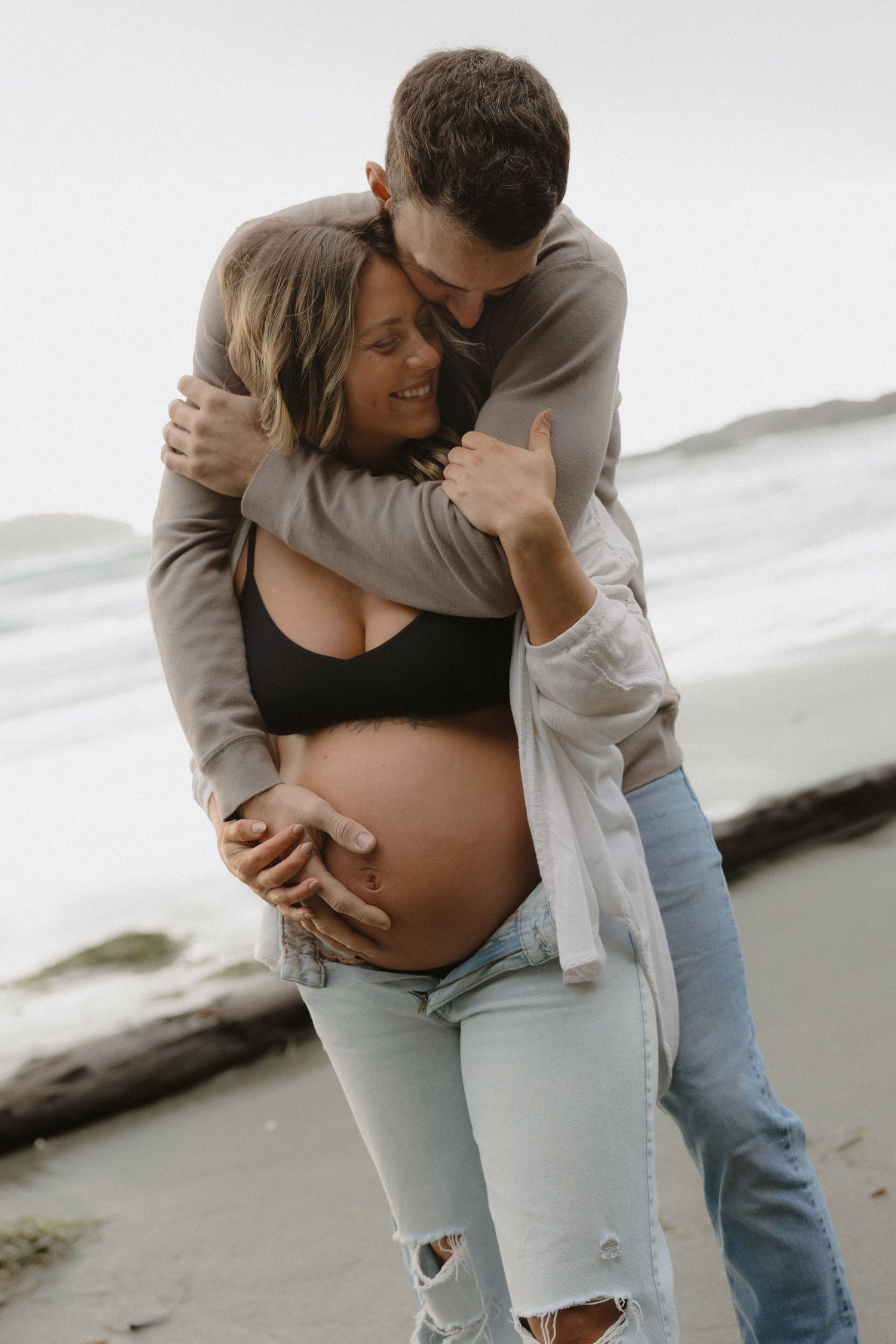 A couple shares tender moments during their beachside maternity session.