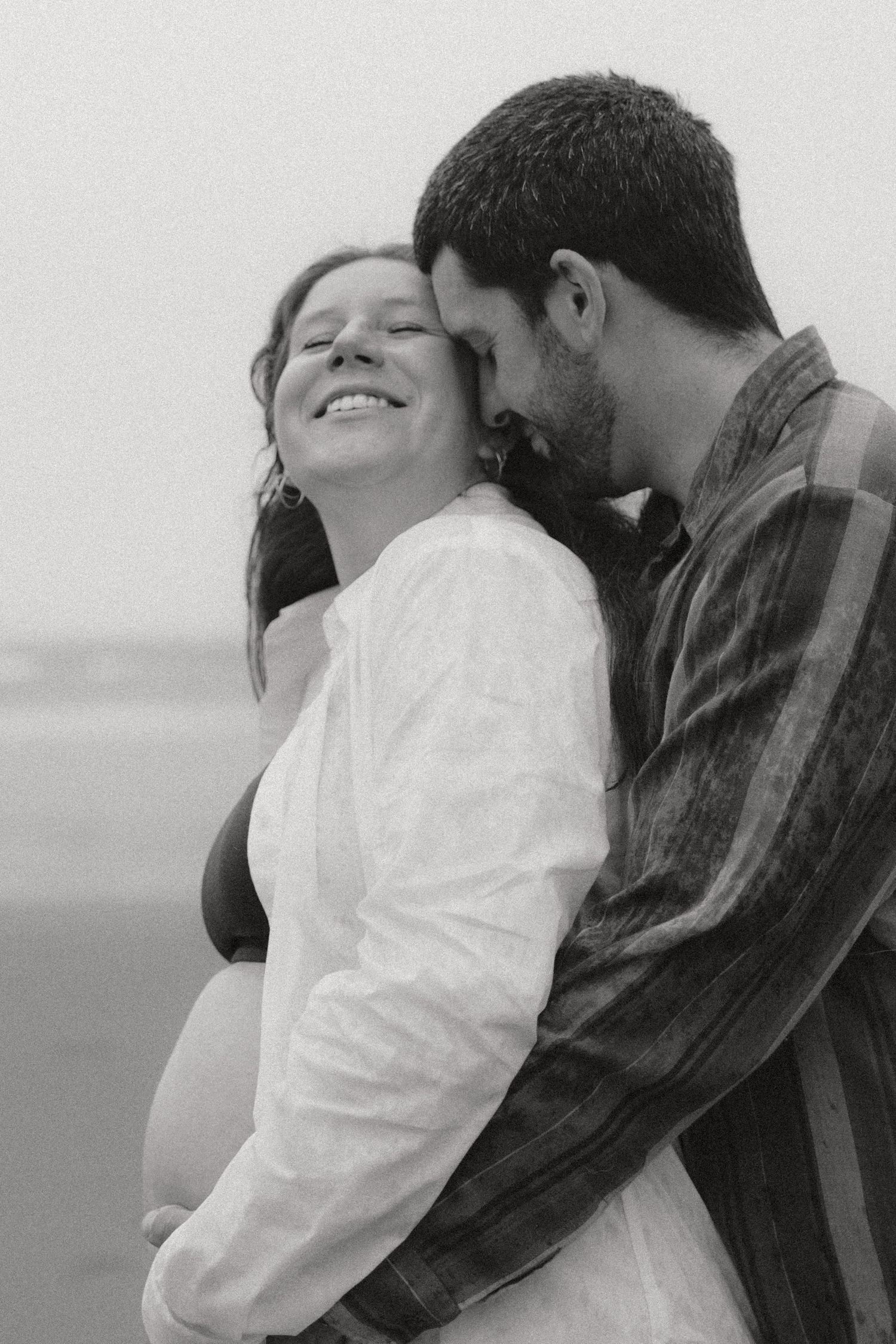 A romantic couple embracing on a beach in black and white photography.