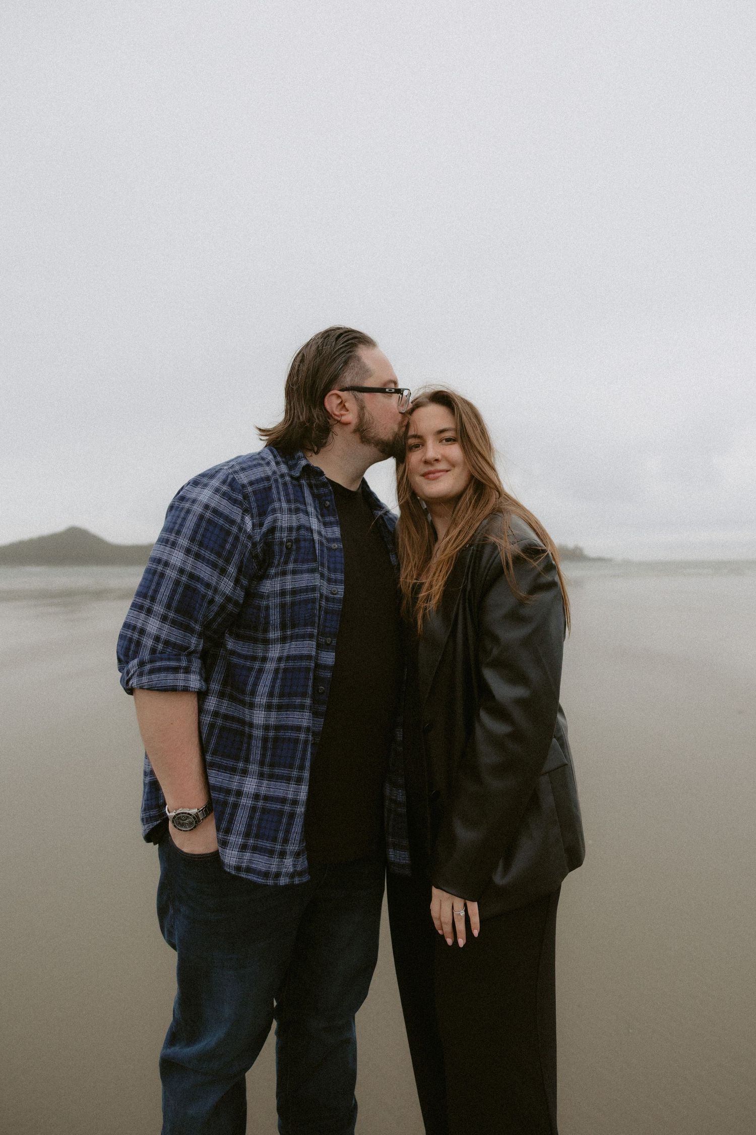 Romantic couple moment captured on a moody Pacific Northwest beach after getting engaged